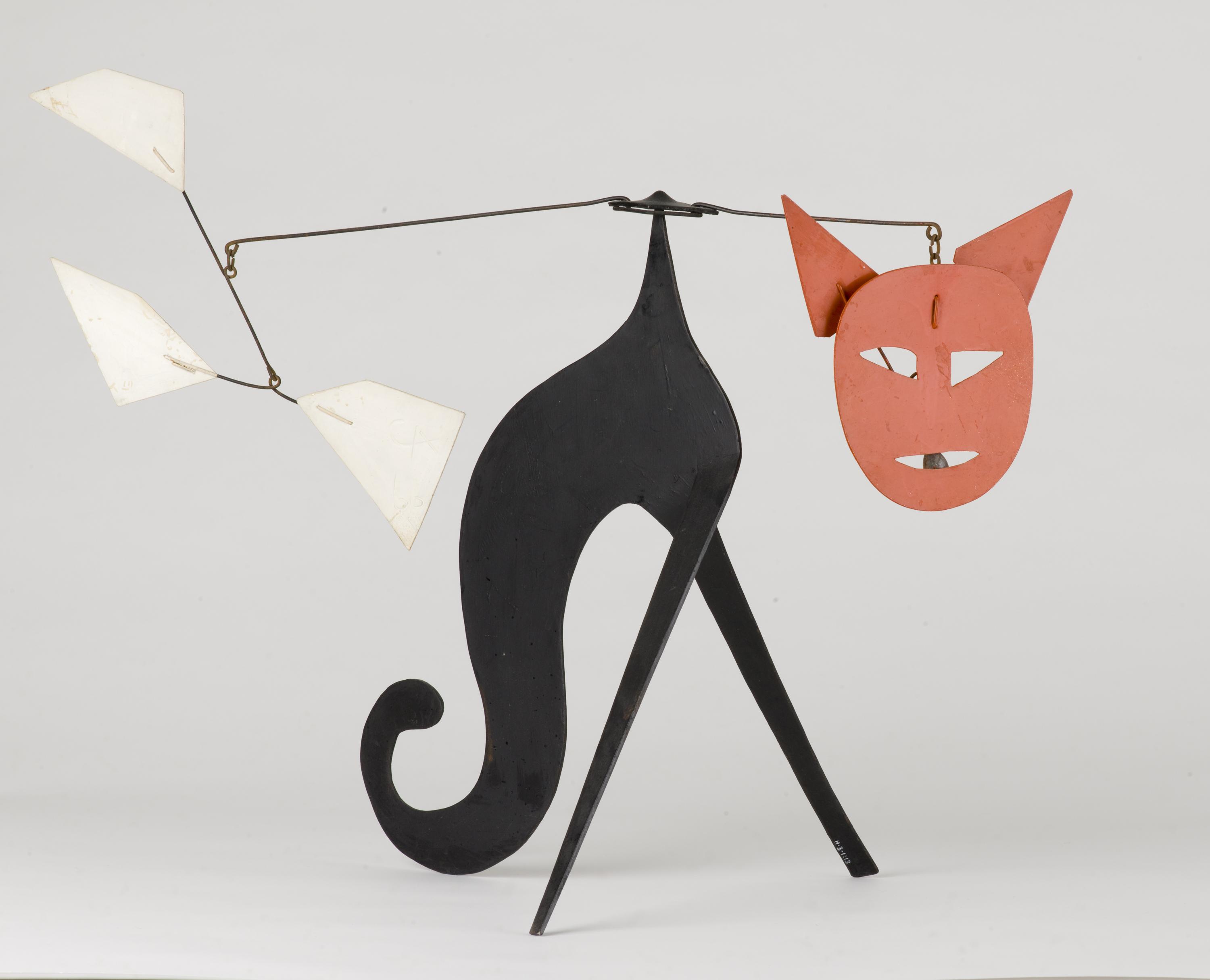 A mobile sculpture resembles a cat with a red face.