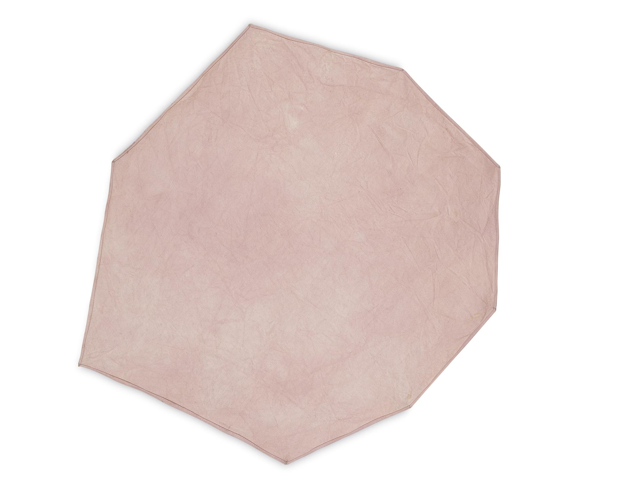 An irregular pale pink octagon is hung at various points on a white wall.
