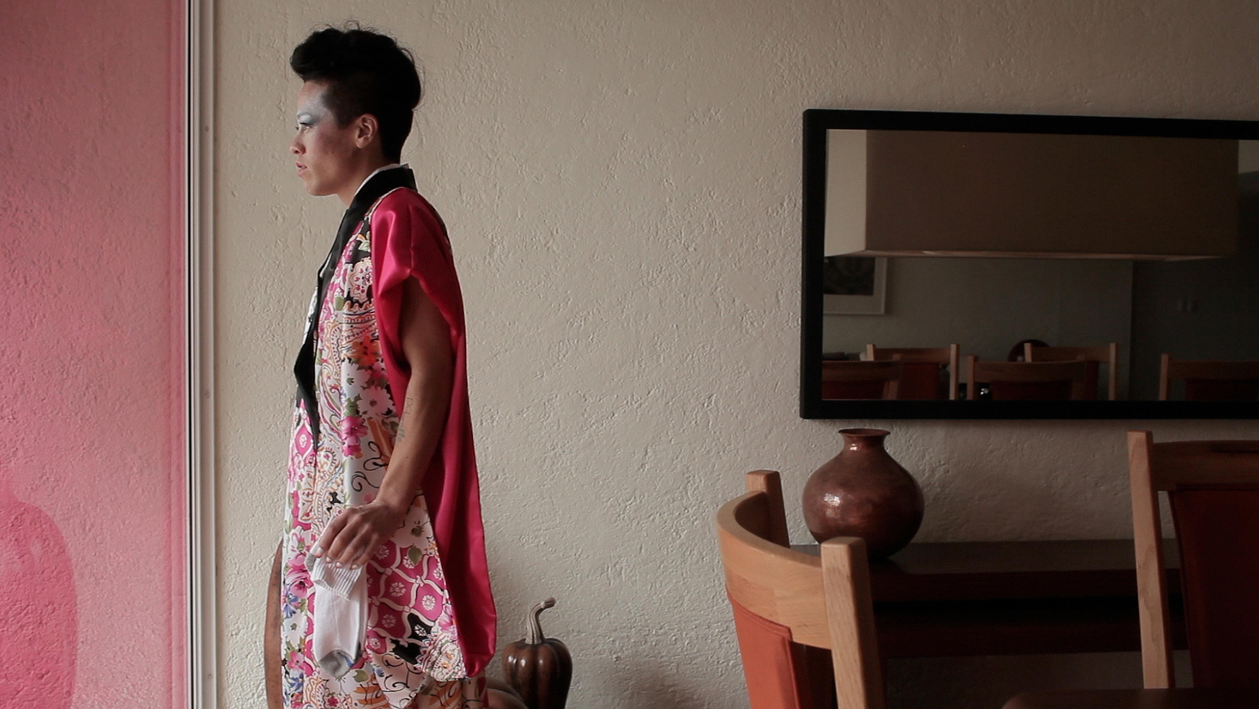 A person stares off to the viewer's left in a hotel room.