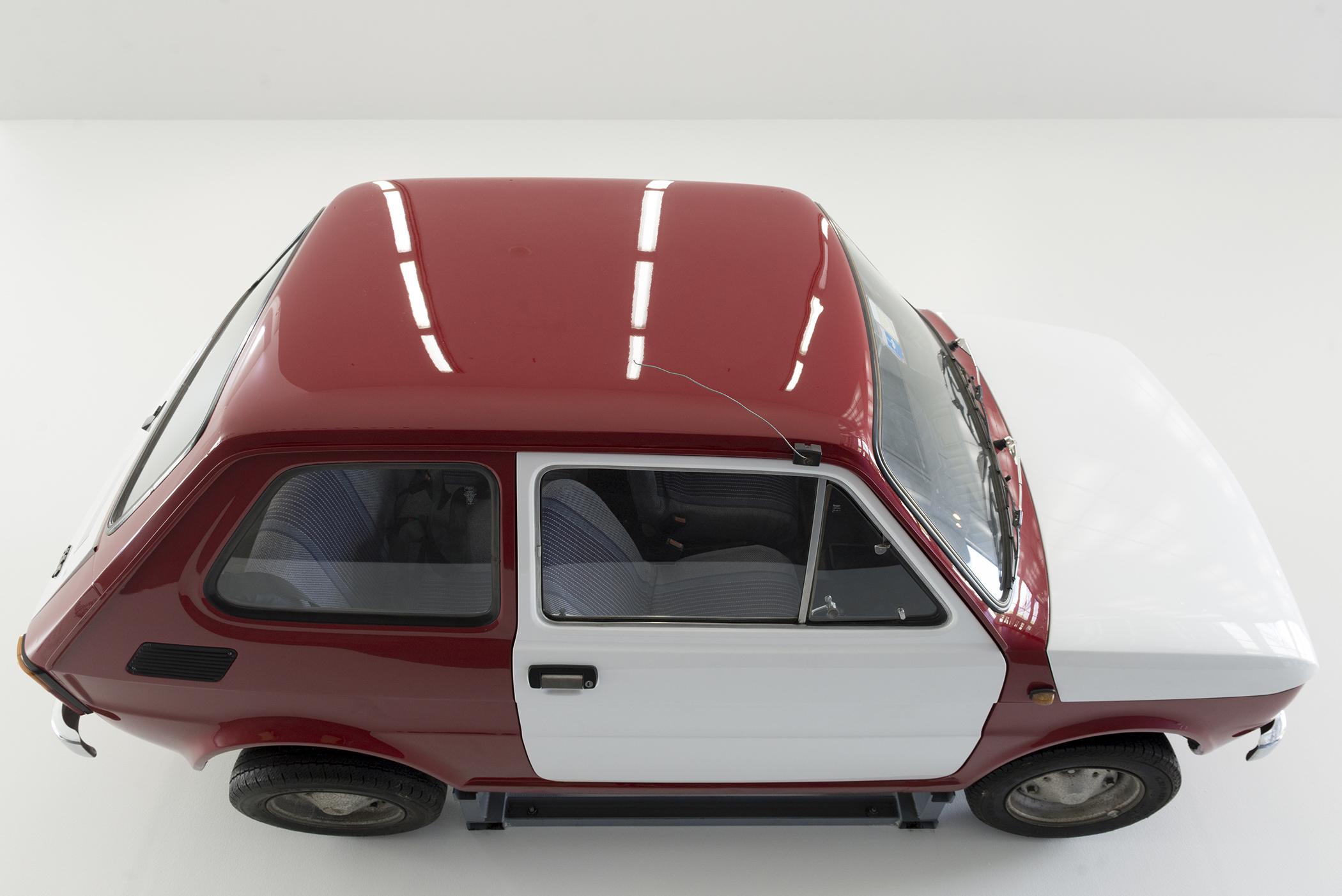 a red and white fiat hanging from a gallery wall