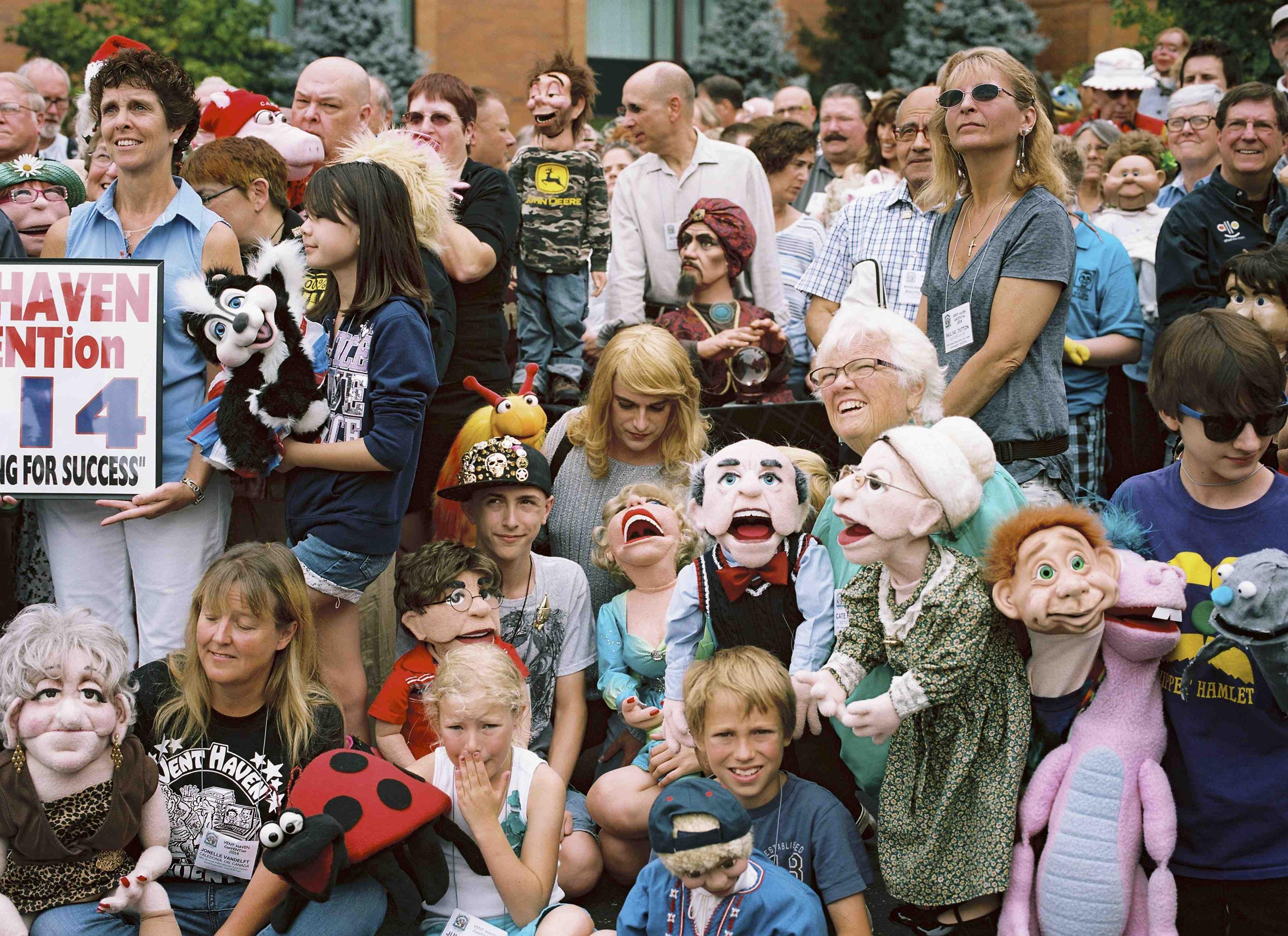 Group photograph of seated and standing people and kids holding various ventriloquist dummies