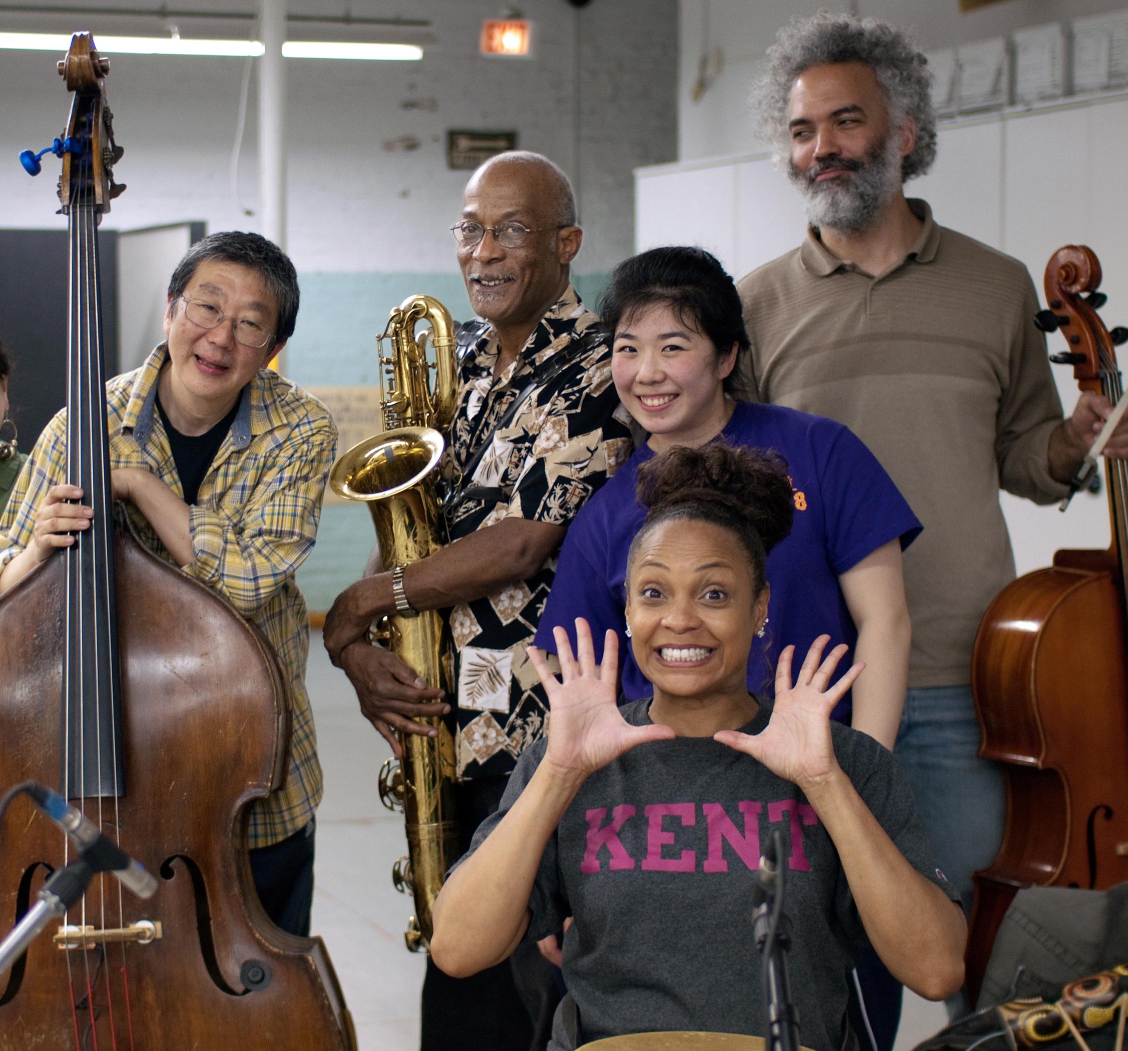 Five musicians posing with instruments