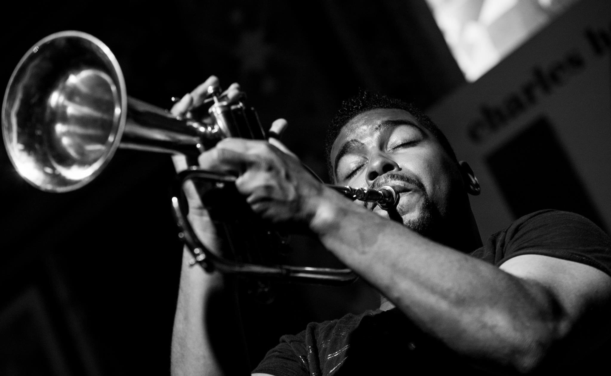 Black-and-white portrait of a man playing the trumpet with eyes closed