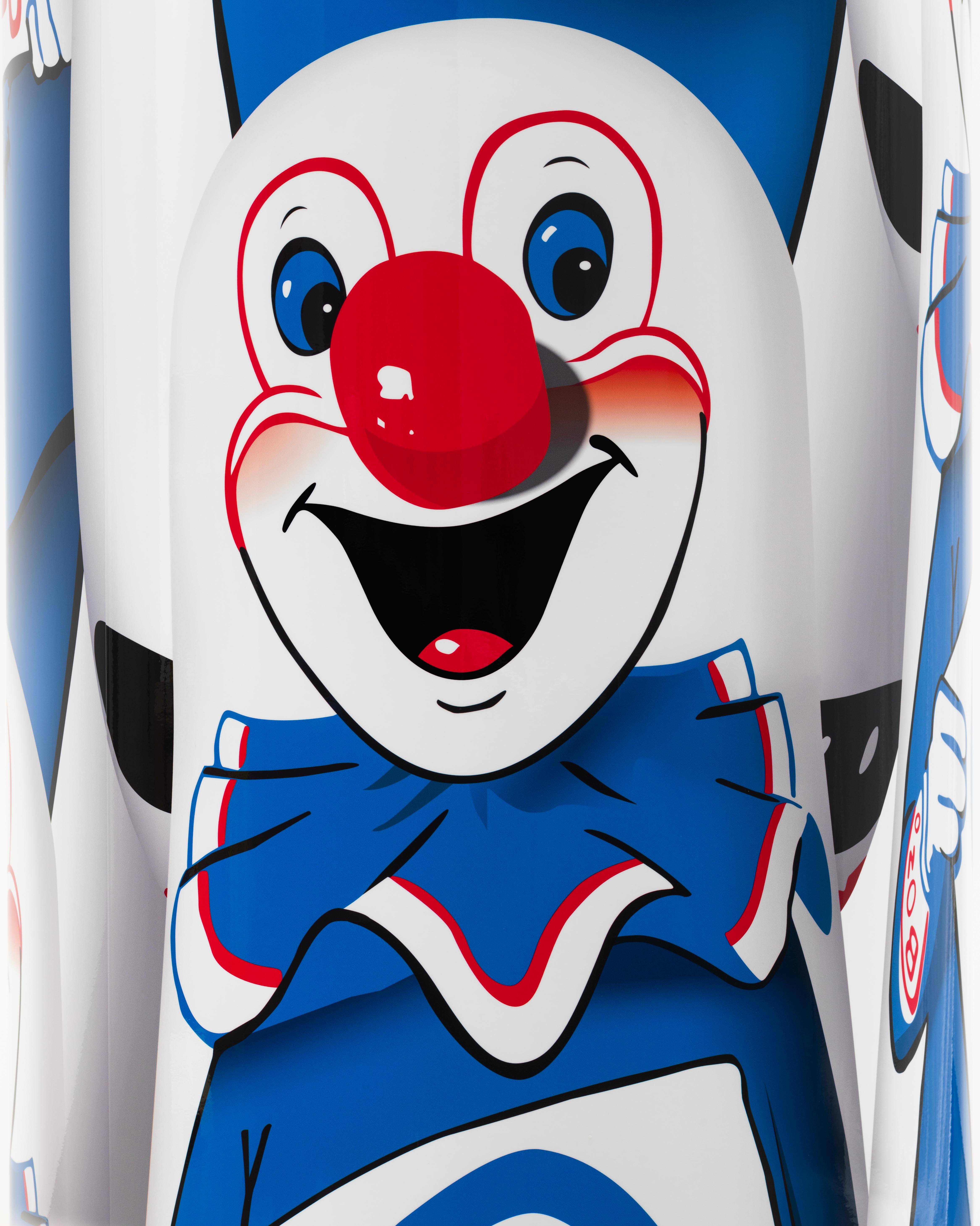 Detail of a cylindrical sculpture wrapped with the image of a white, red, and blue clown