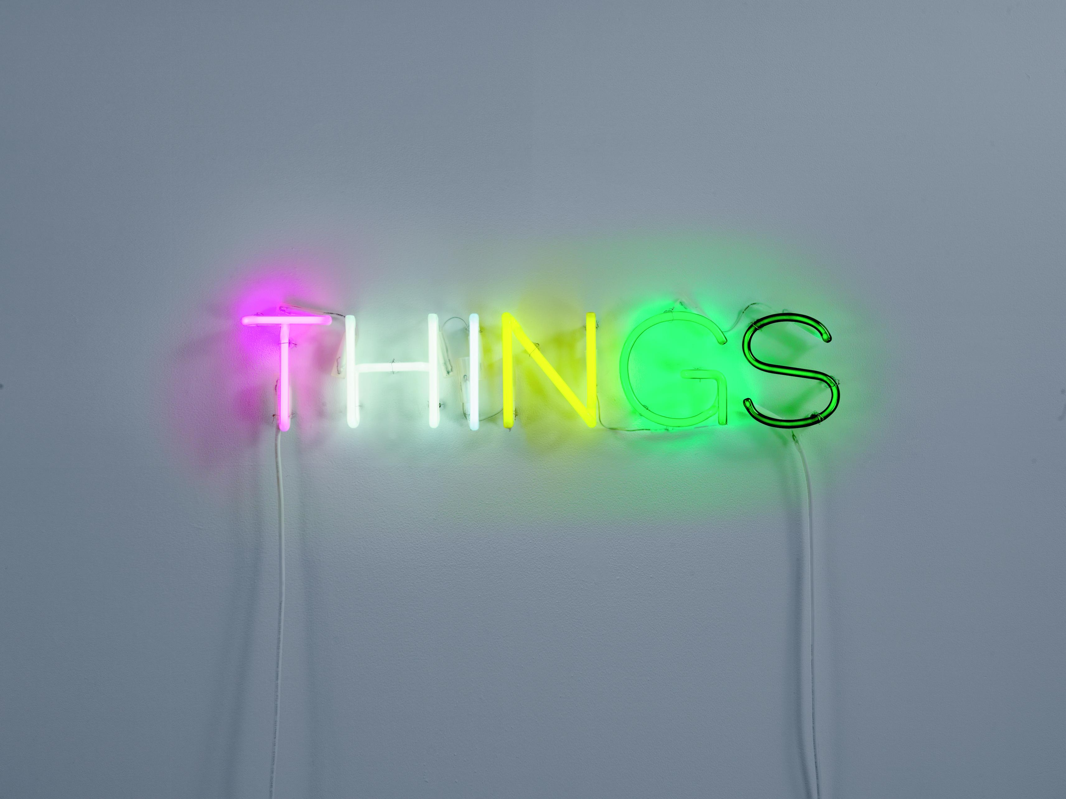 A glowing neon-light sculpture spells out the word "THINGS."