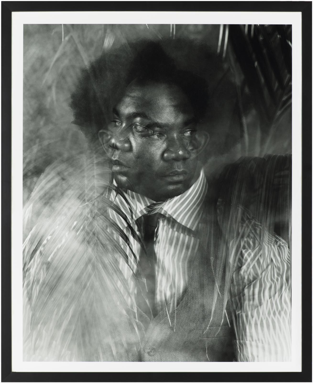 This black and white vertical portrait portrays a dark-skinned person with two faces, one looking left and the other looking right, with palm-like fronds surrounding the figure.