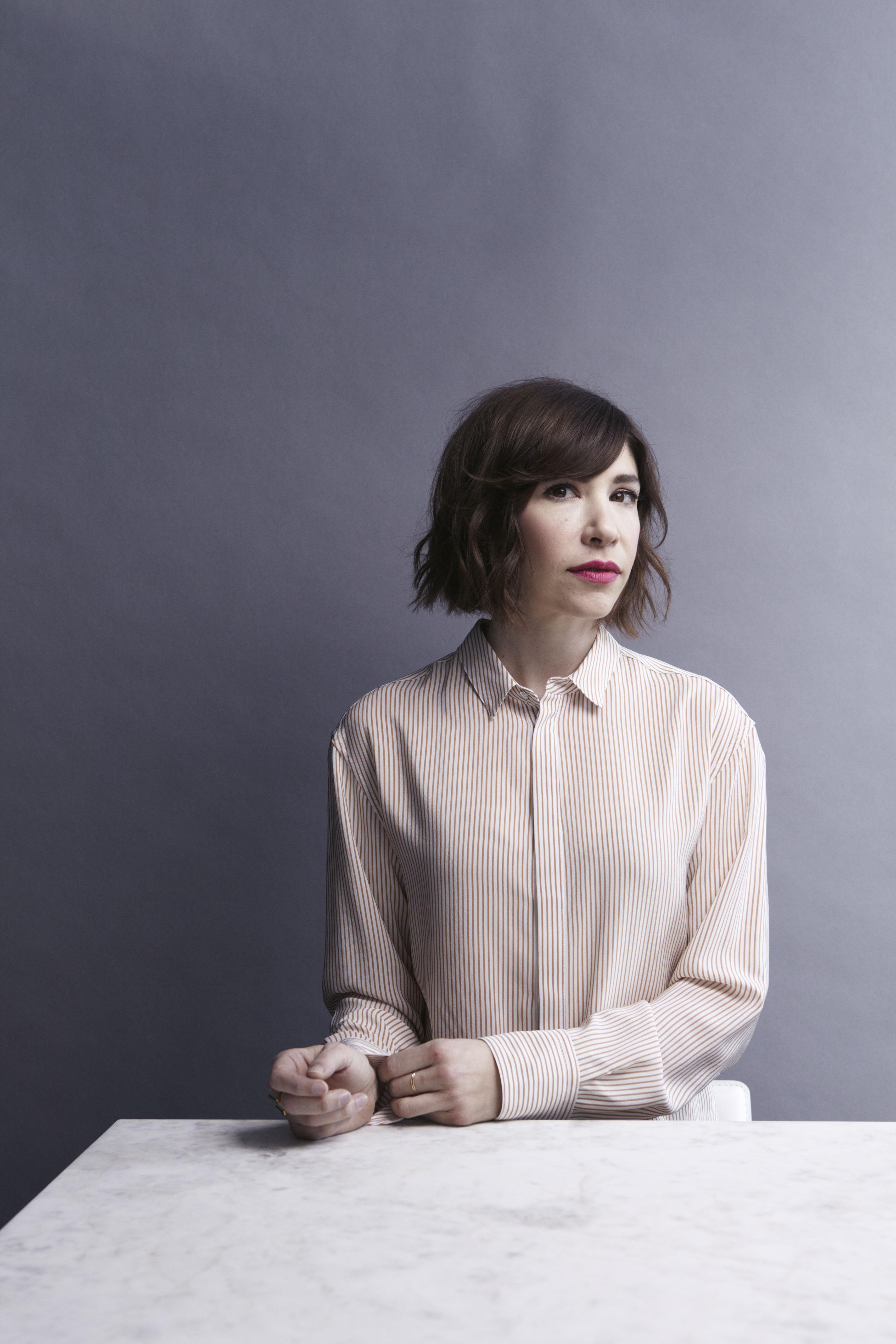 A portrait of a woman with dark hair wearing a light colored blouse