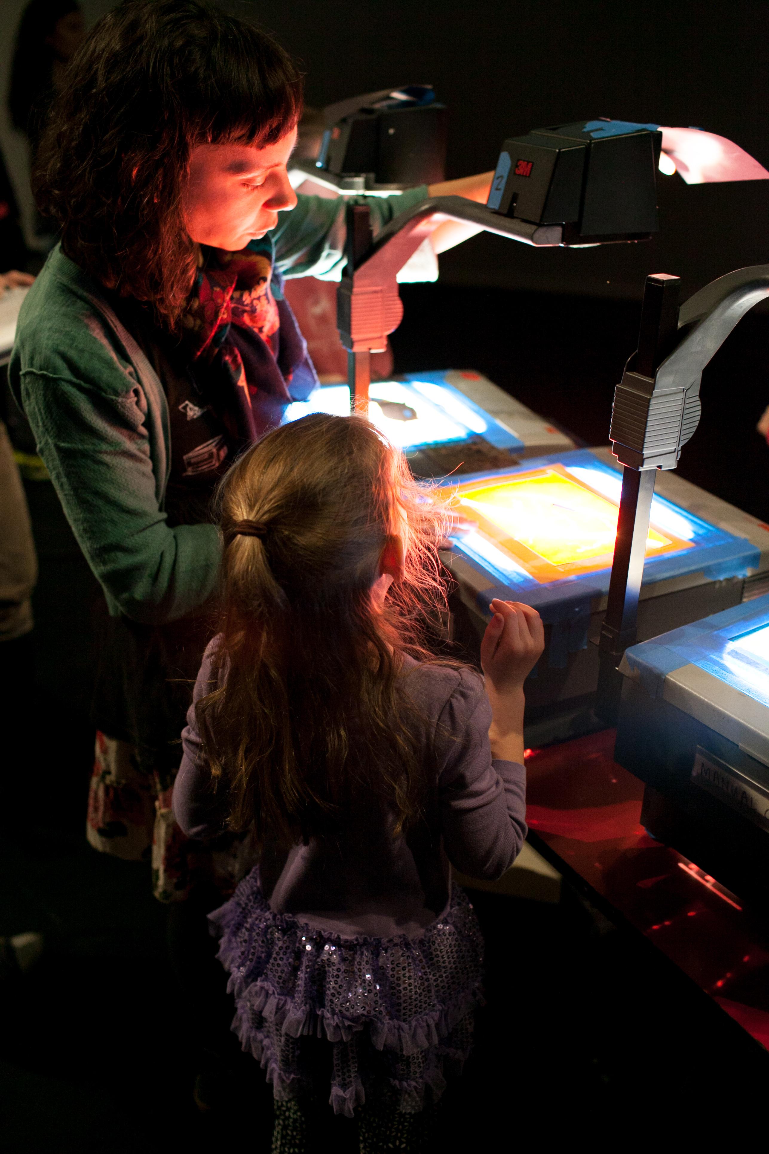 A woman and girl position a transparency on an overhead projector.