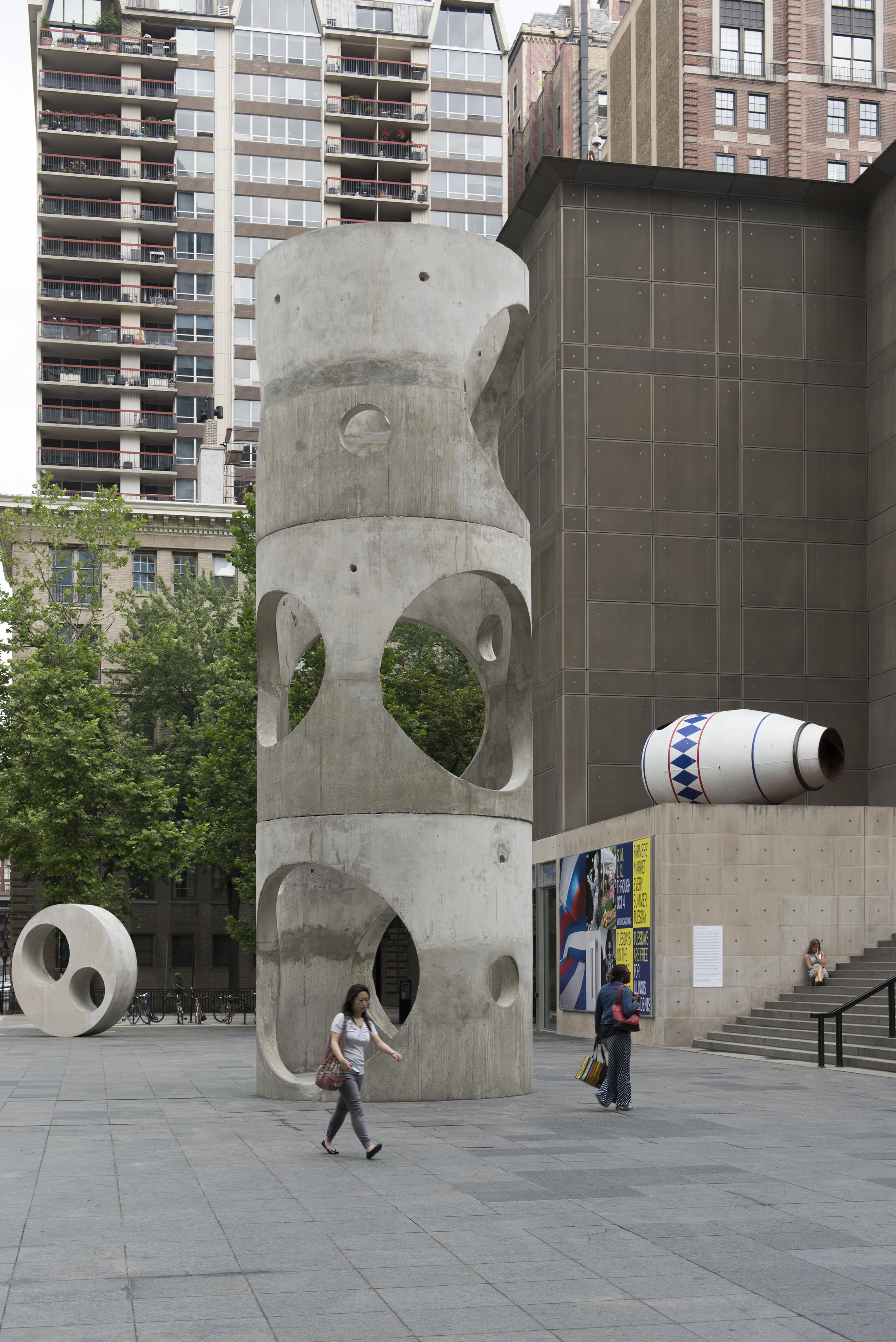 People walking across the MCA Plaza with three large sculptures
