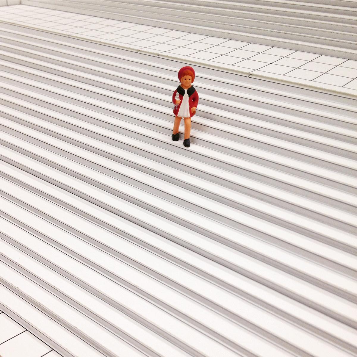 A close-up of a black-and-white model of the MCA's front stairs with a little girl figurine in a white dress and a red jacket and beret.