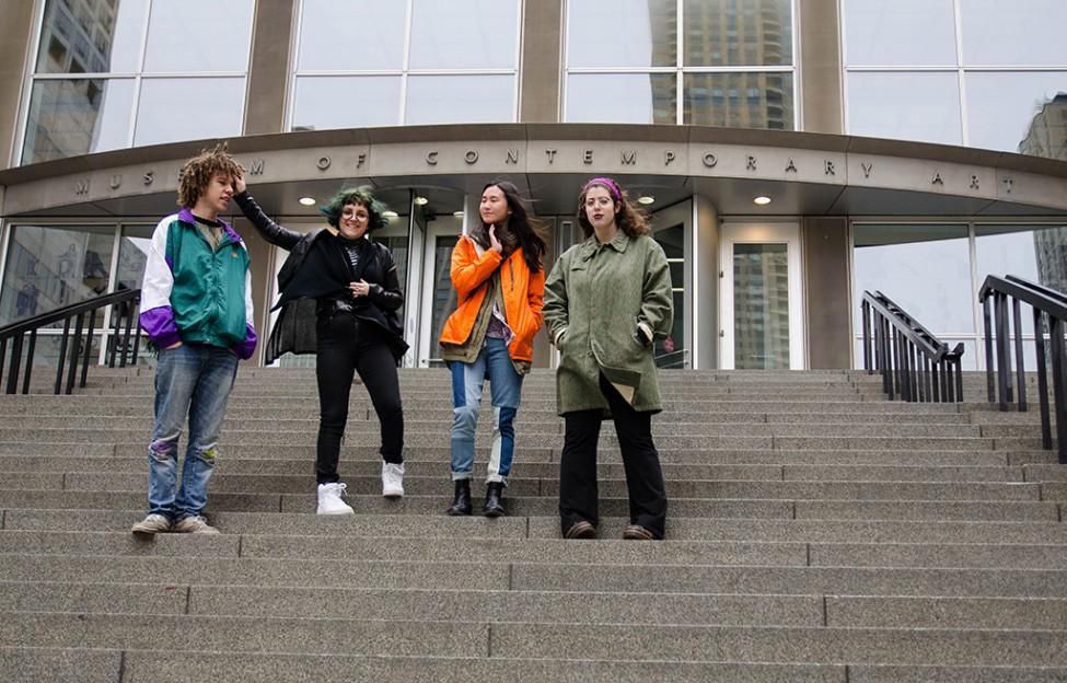 Four young adults pose playfully for a photograph on the stairs of the entrance to the MCA.