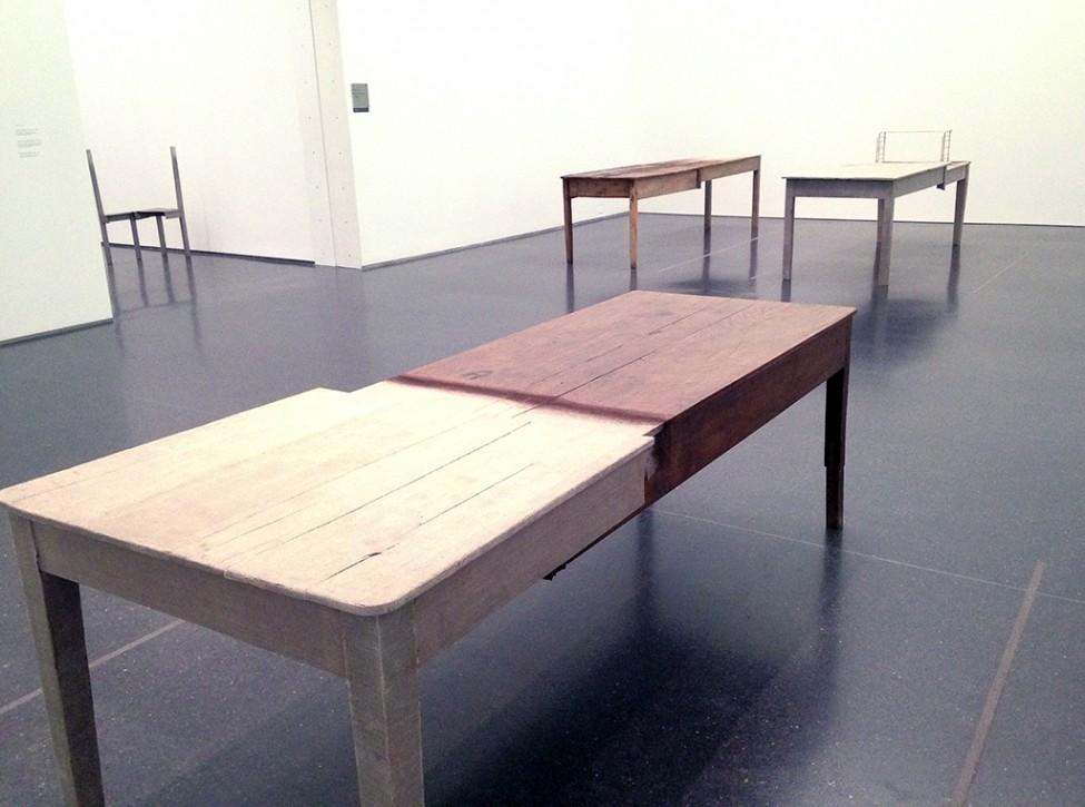 A room holds three tables, each constructed from two halves of different kinds of wood.