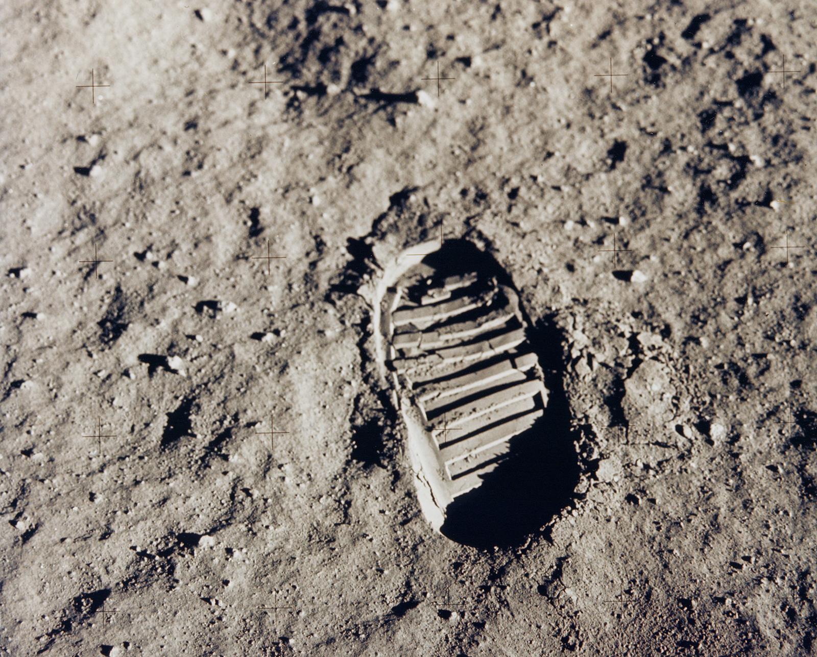 This sepia image of a boot print in moon dust is covered by a four-by-five grid of faint plus marks.