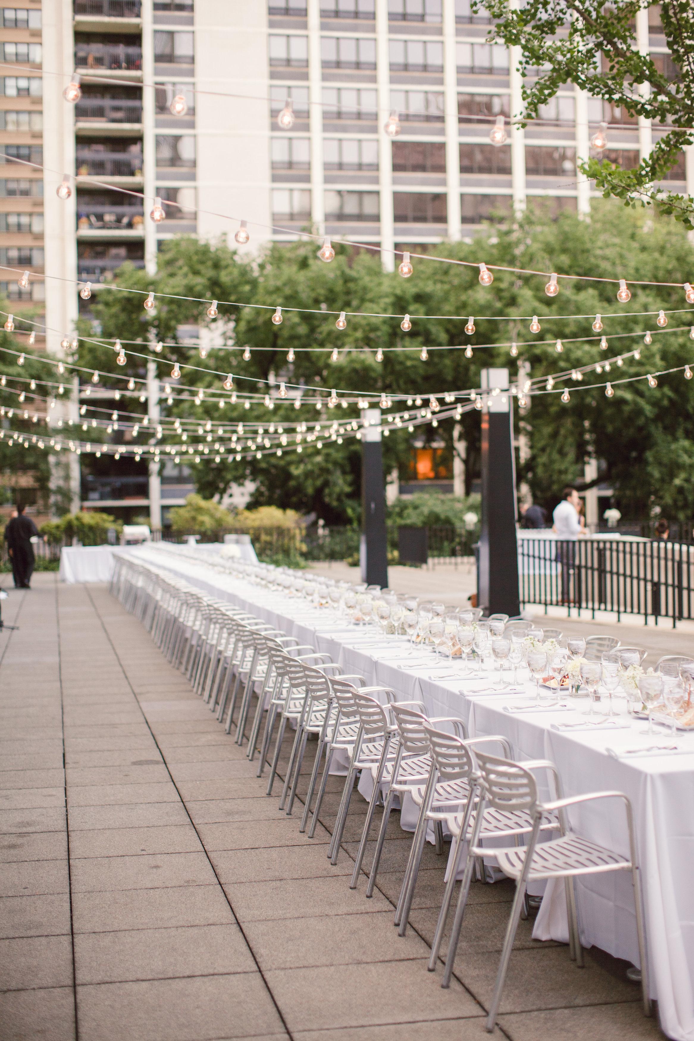 The MCA's terrace is set with a long white banquet table and delicate strands of naked lightbulbs above.