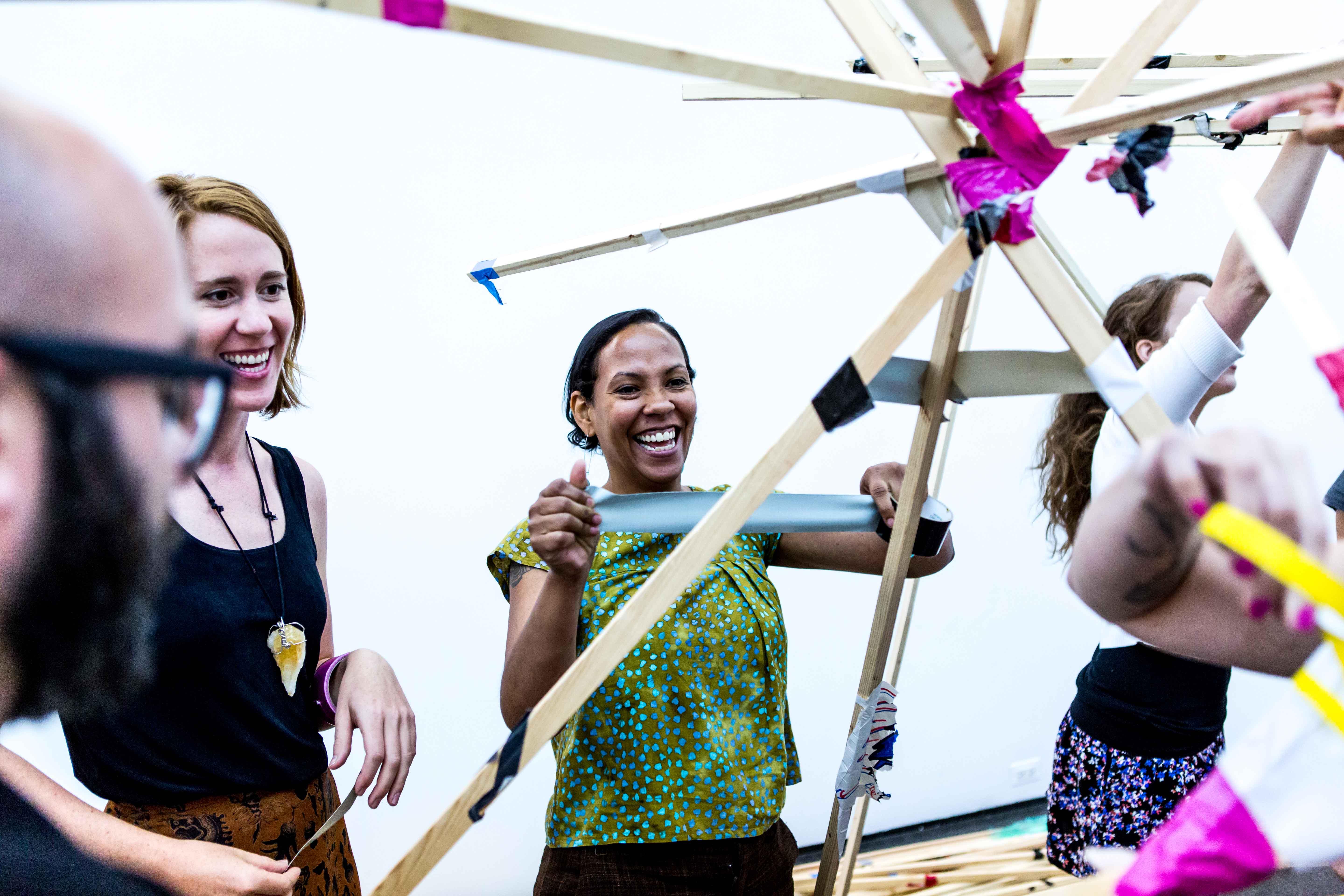 People making a structure with tape and long beams of wood