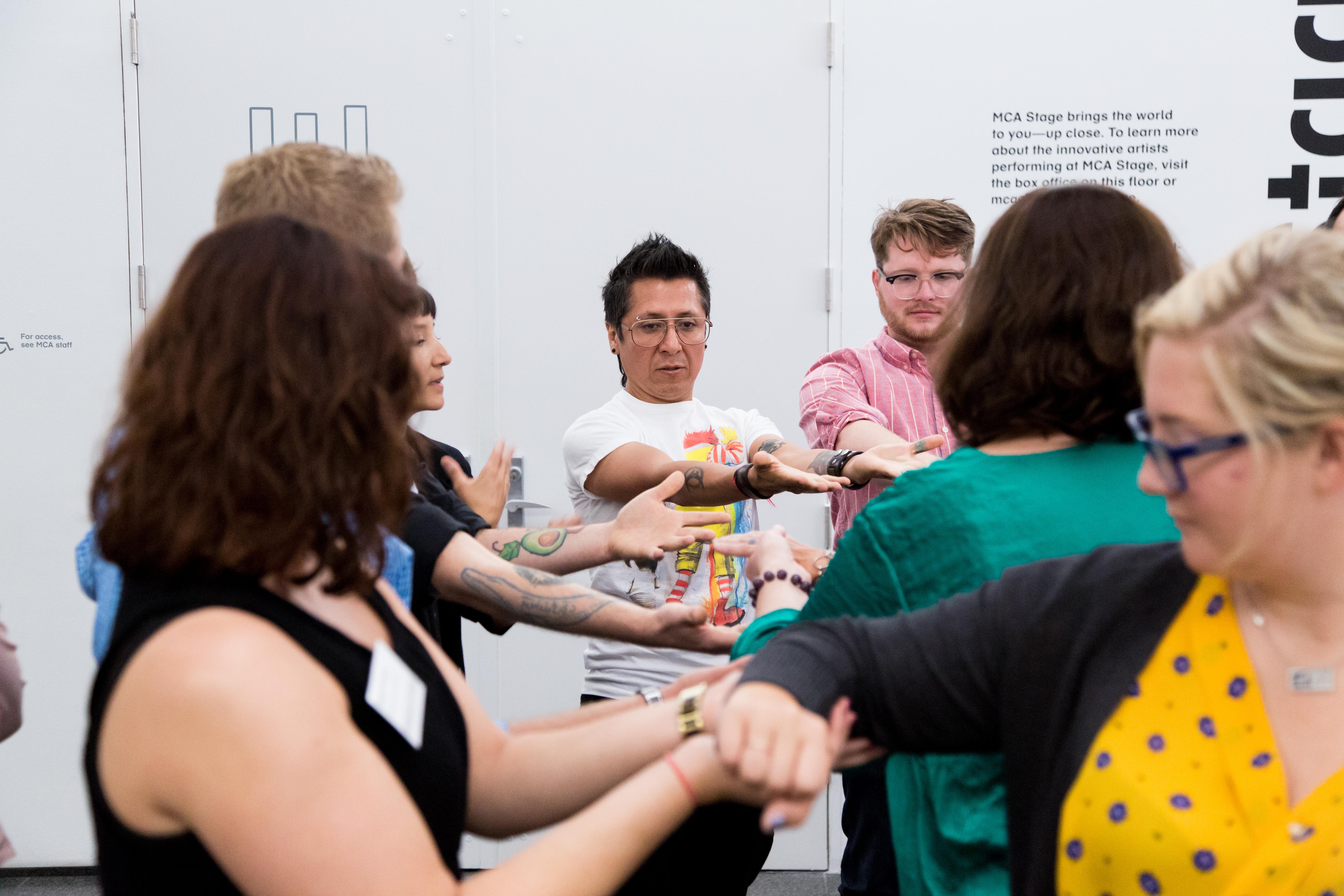 A group of adults, arms outstretched, participate a group activity.