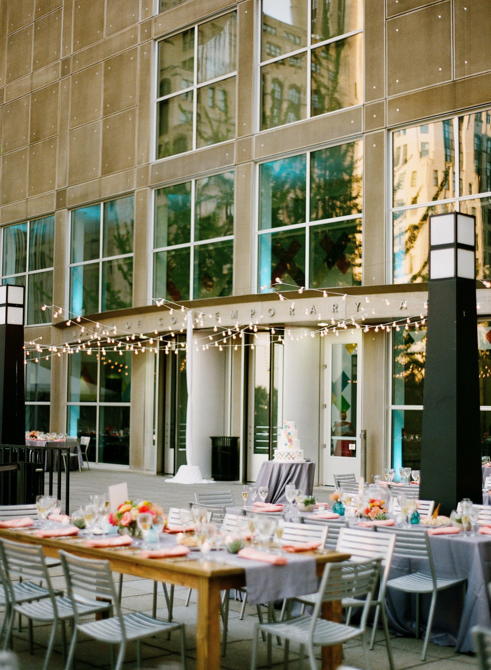 The MCA terrace is decorated with banquet tables, decorative lights, and a wedding cake.