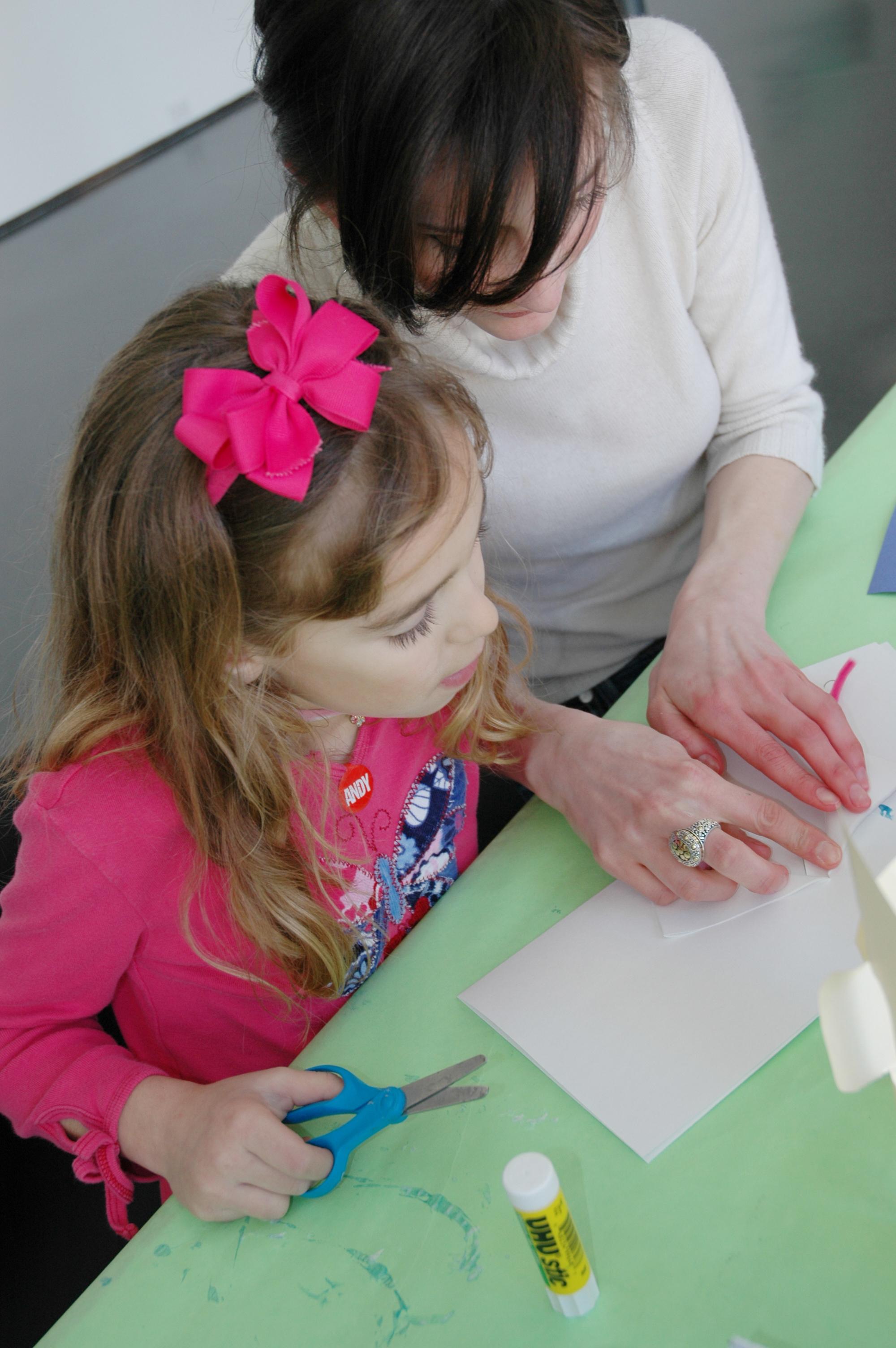 View from above of a light-skinned woman and a young girl working at a craft table.