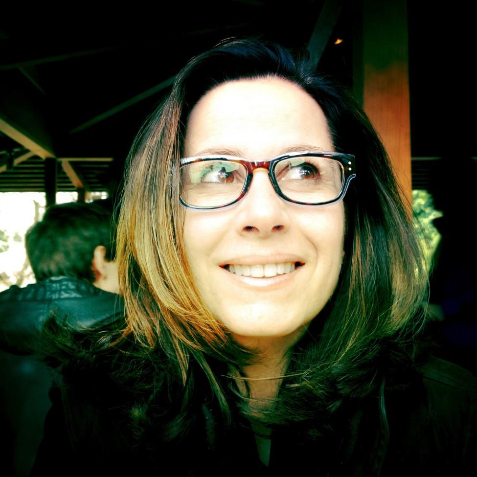 A light-skinned woman with black hair with caramel highlights wears horn-rimmed, tortoiseshell glasses.