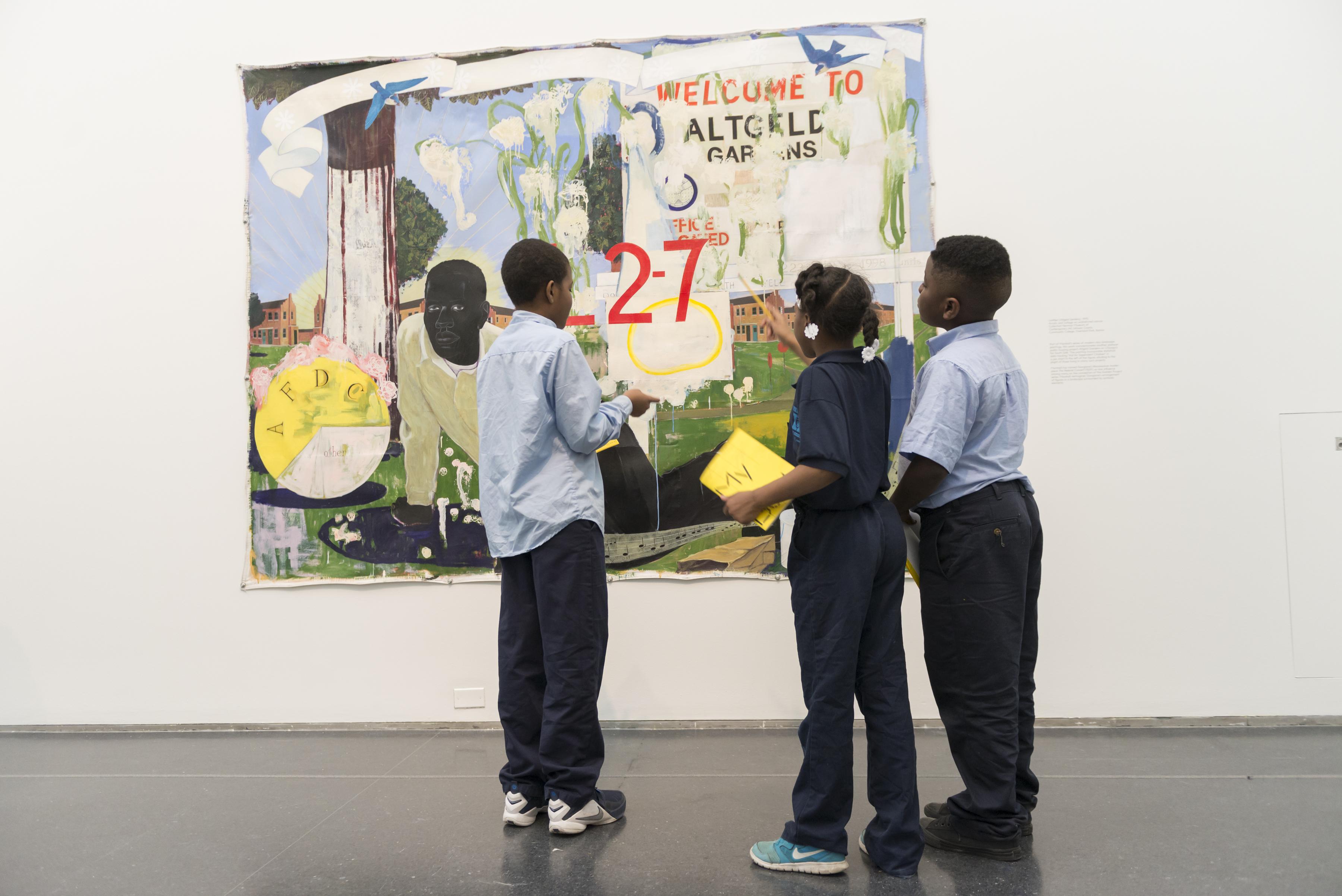 Three young black school children in school uniforms standing in front of a painting on a school tour.