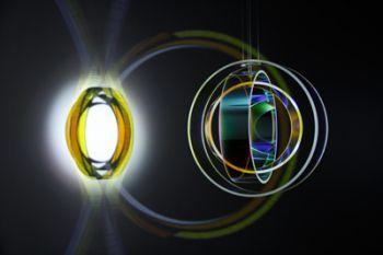 One sphere of yellow and orange light is connected to another sphere of multicolored circles by two larger yellow and orange circles in the dark background.