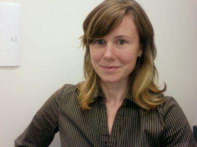 A person with long hair wearing a brown striped shirt stares back at you.