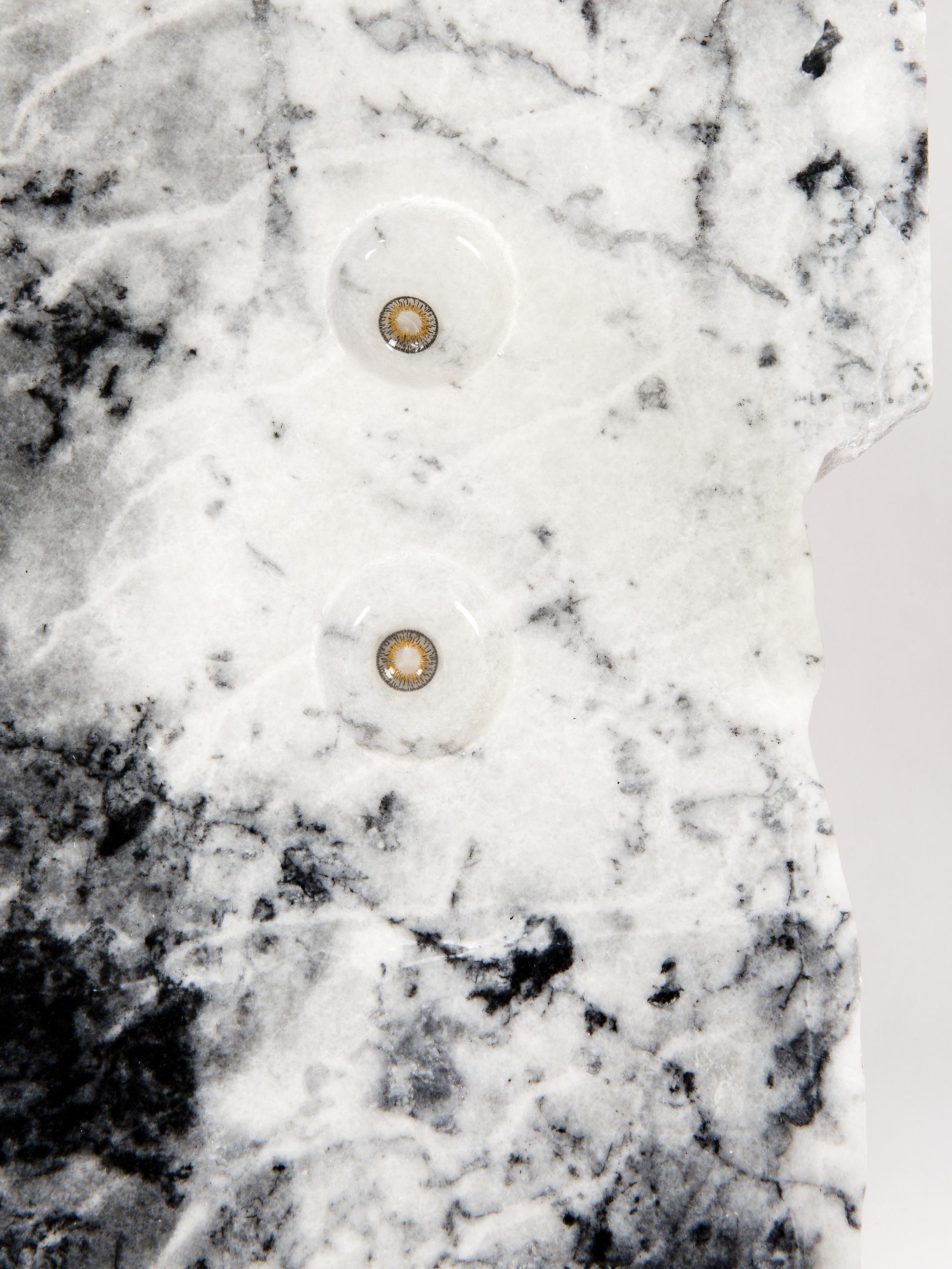 Two contact lenses with brown and orange irises and clear edges sit side by side on a piece of black-and-white marble.