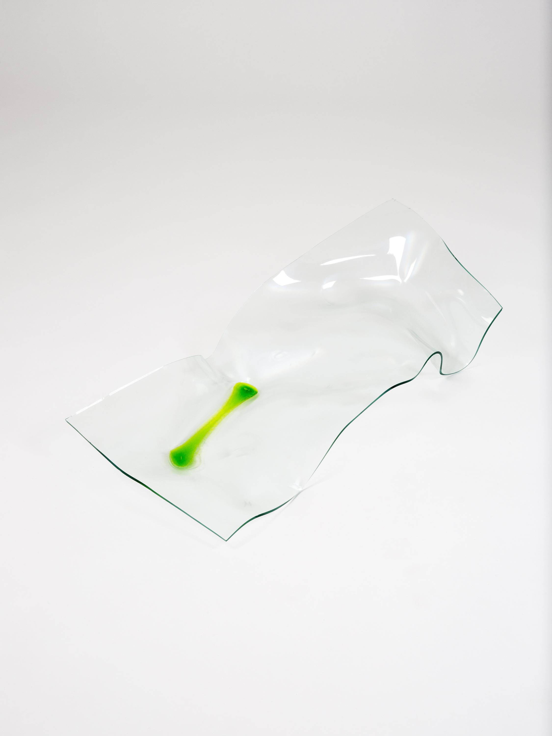 An image of an undulating sheet of clear glass, seemingly melted into this shape, on top of which is pooled a strip of bright green liquid.