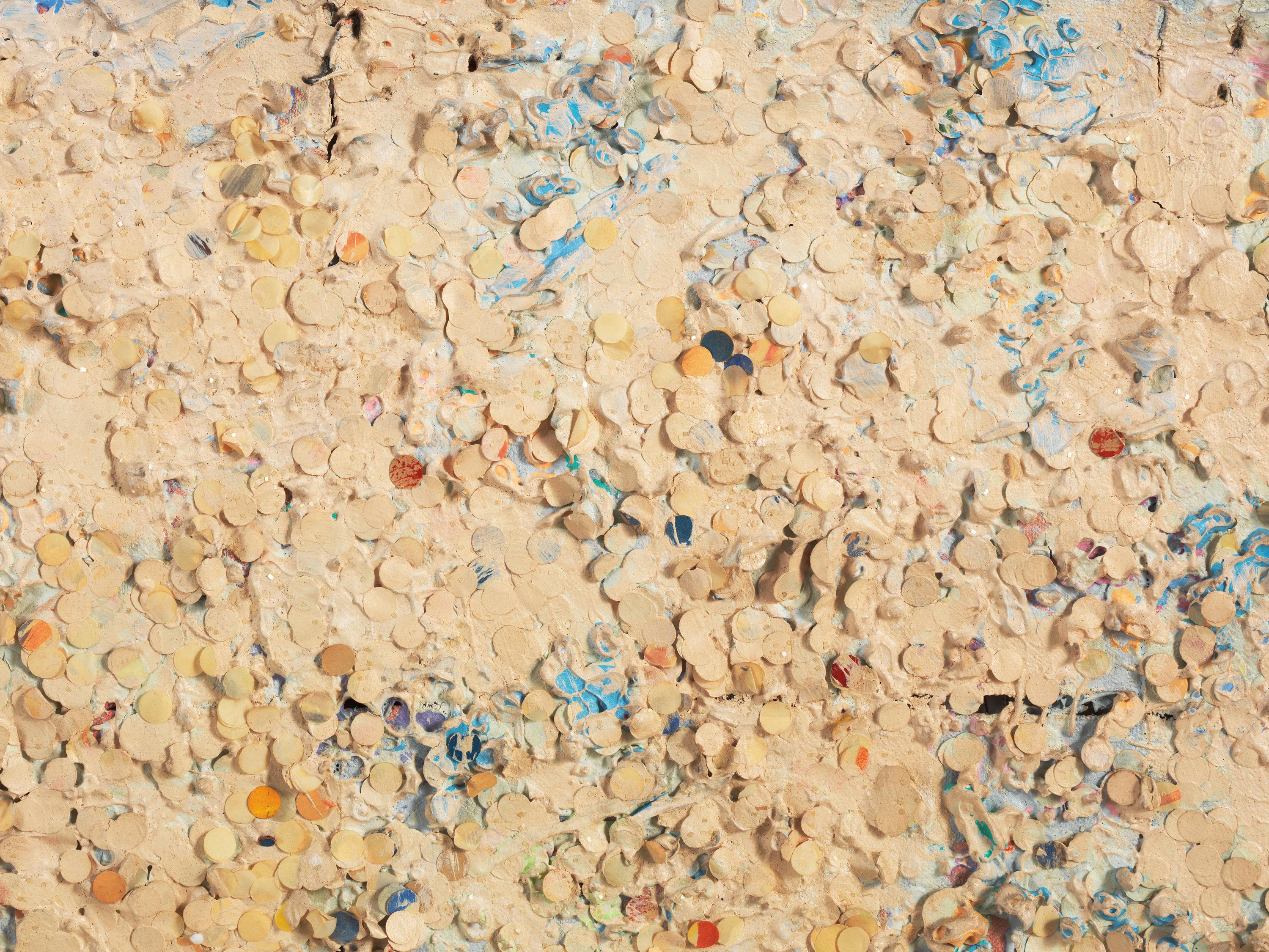 A beige, textured surface covered in small circles is accented with hints of blue, orange, and red paint.