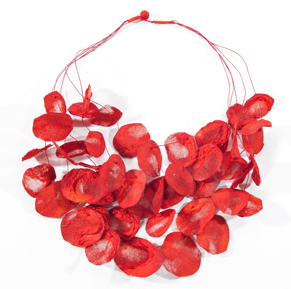 A necklace with dozens of fire red rose petals that are hand fashioned from mesh and paper and threaded through multiple strands.