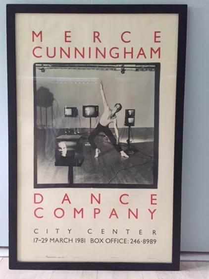 A framed poster of Merce Cunningham on the floor, leaning on the wall.