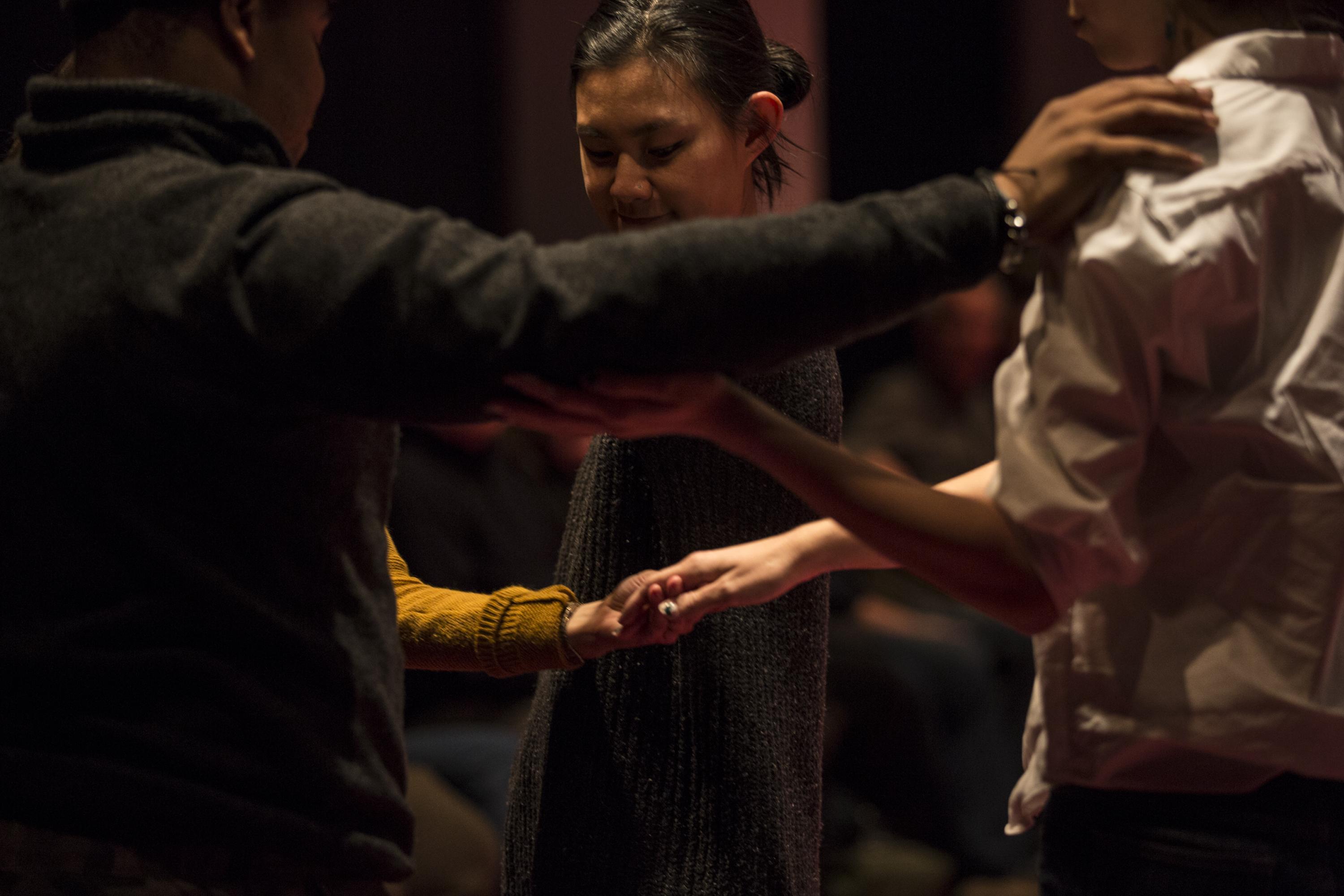 Three adults and a child holding hands appear to be praying or maybe dancing.