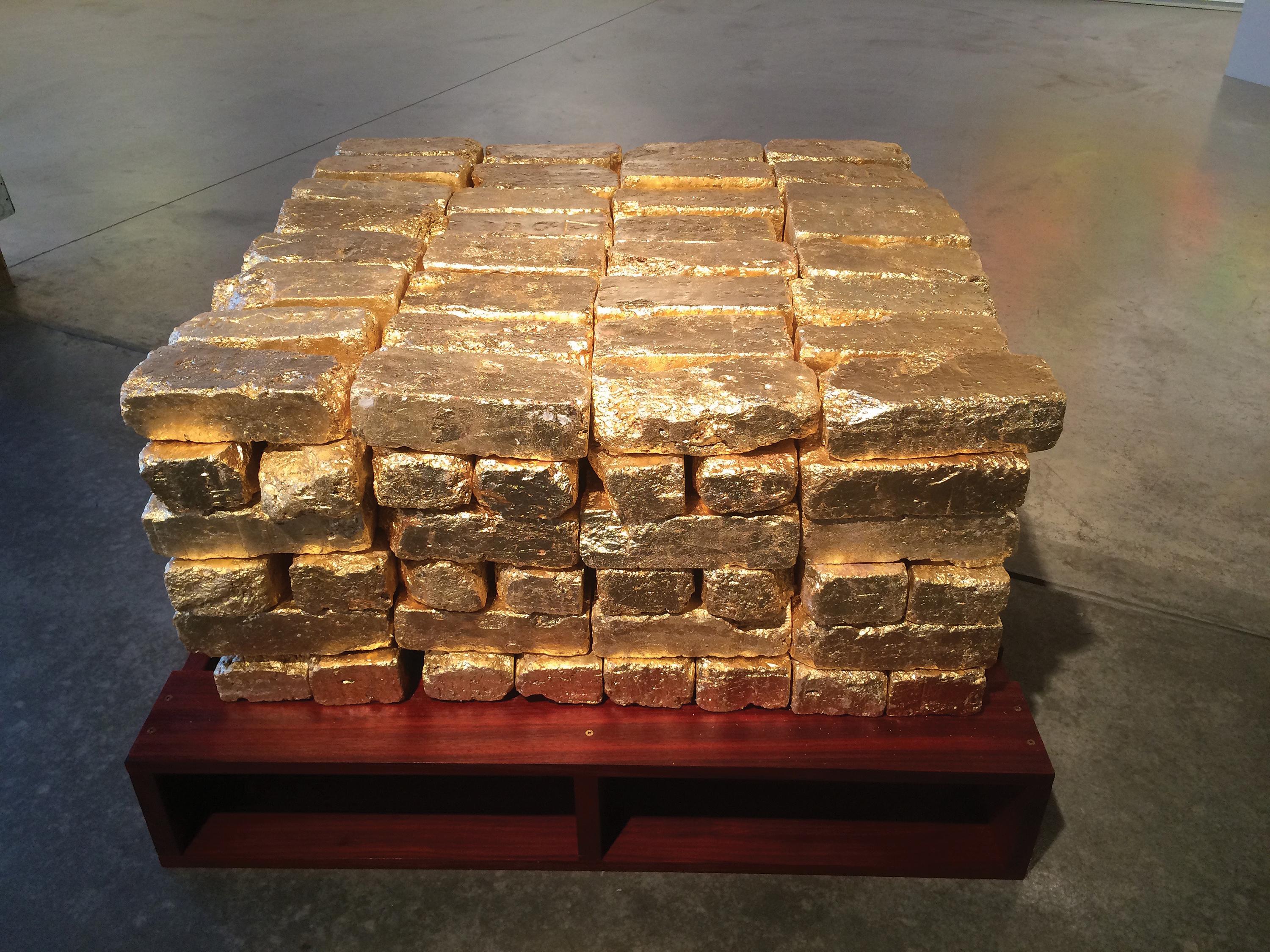 Six rows of gold-leafed bricks are stacked atop a wooden pallet.