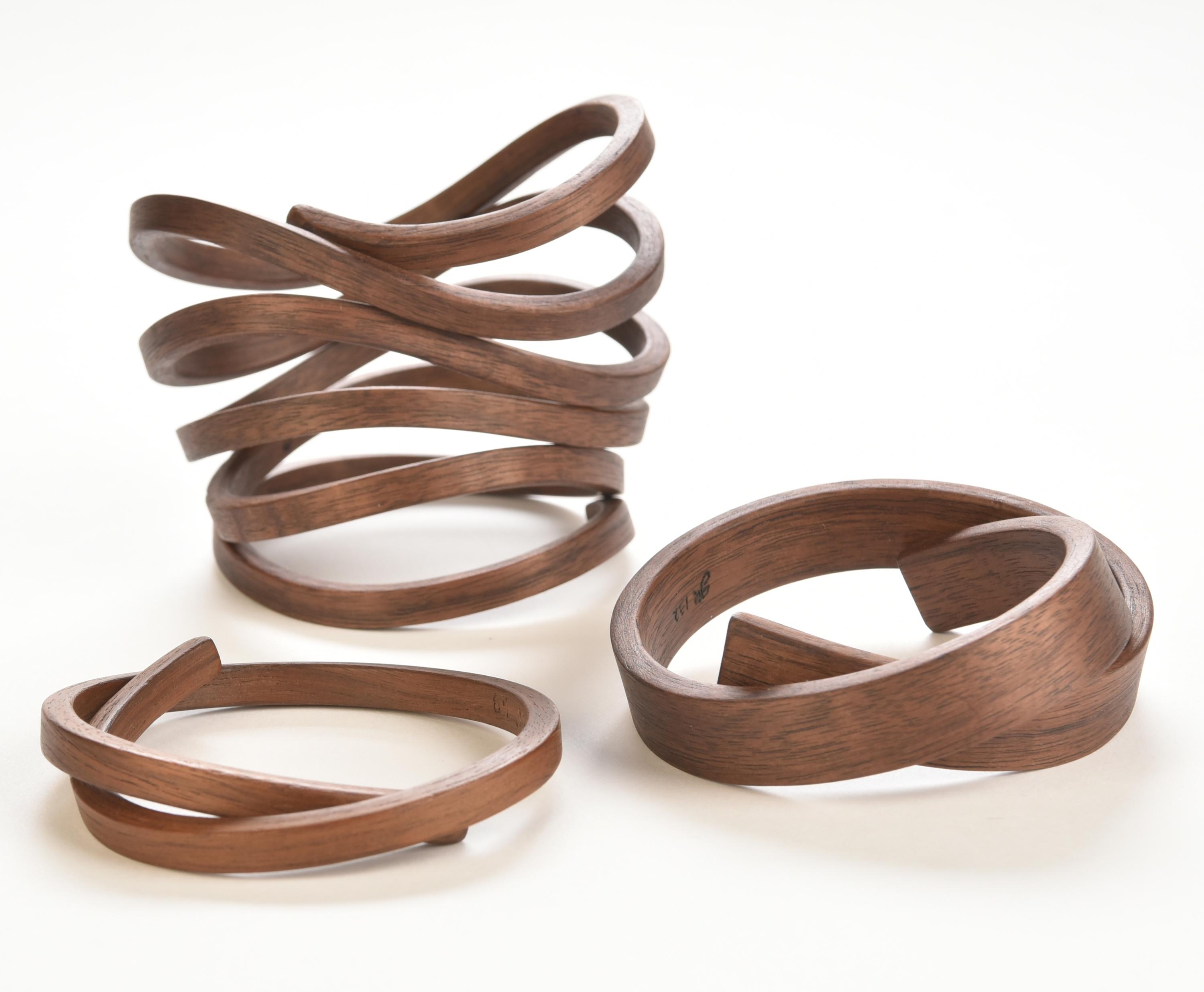 Three wooden bracelets of varying thicknesses are each shaped into distinct spirals.