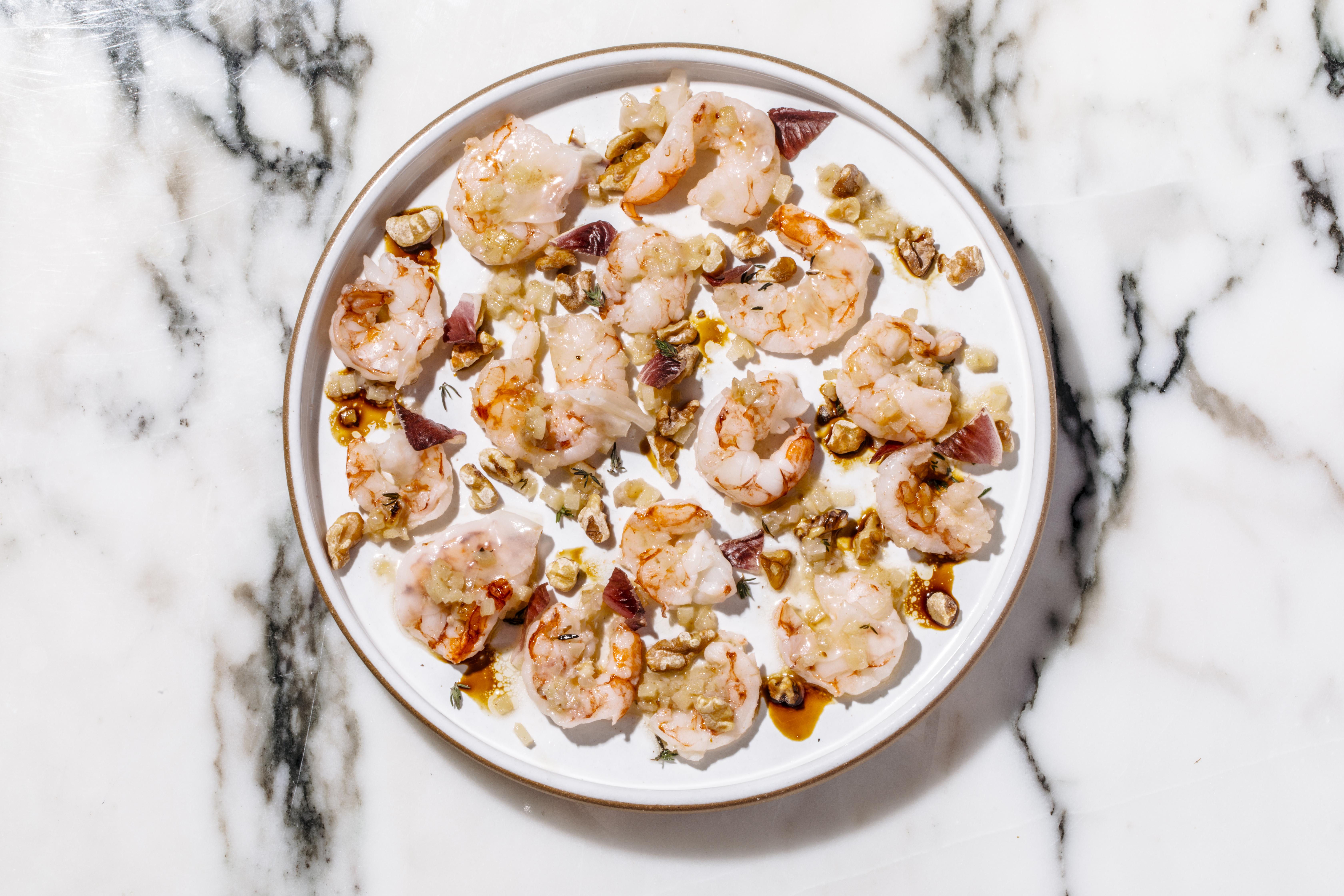 A delicate, artistically plated dish served on a white plate atop a white marble surface.