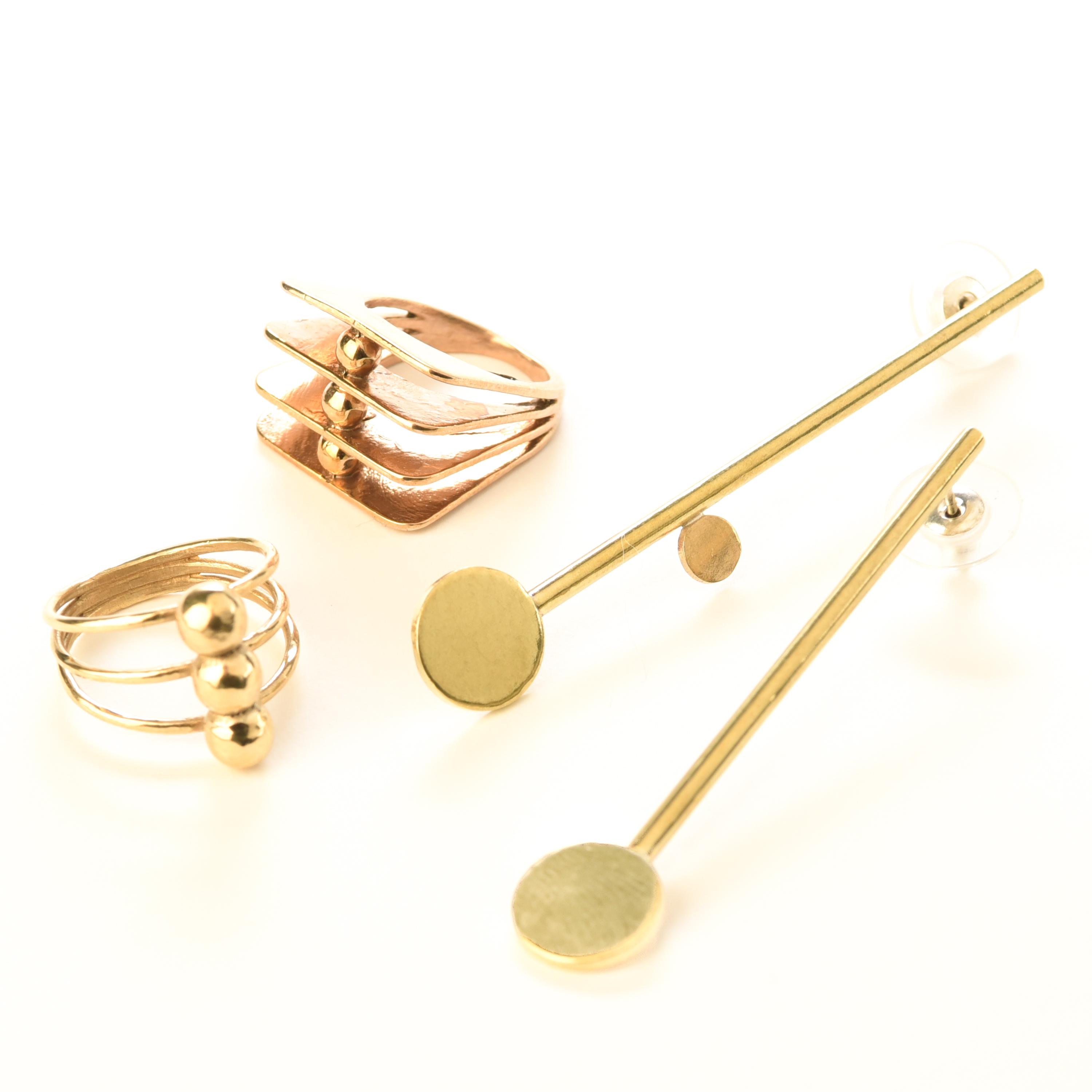 Two unique rings and a pair of earrings share a motif of gold circles and lines.