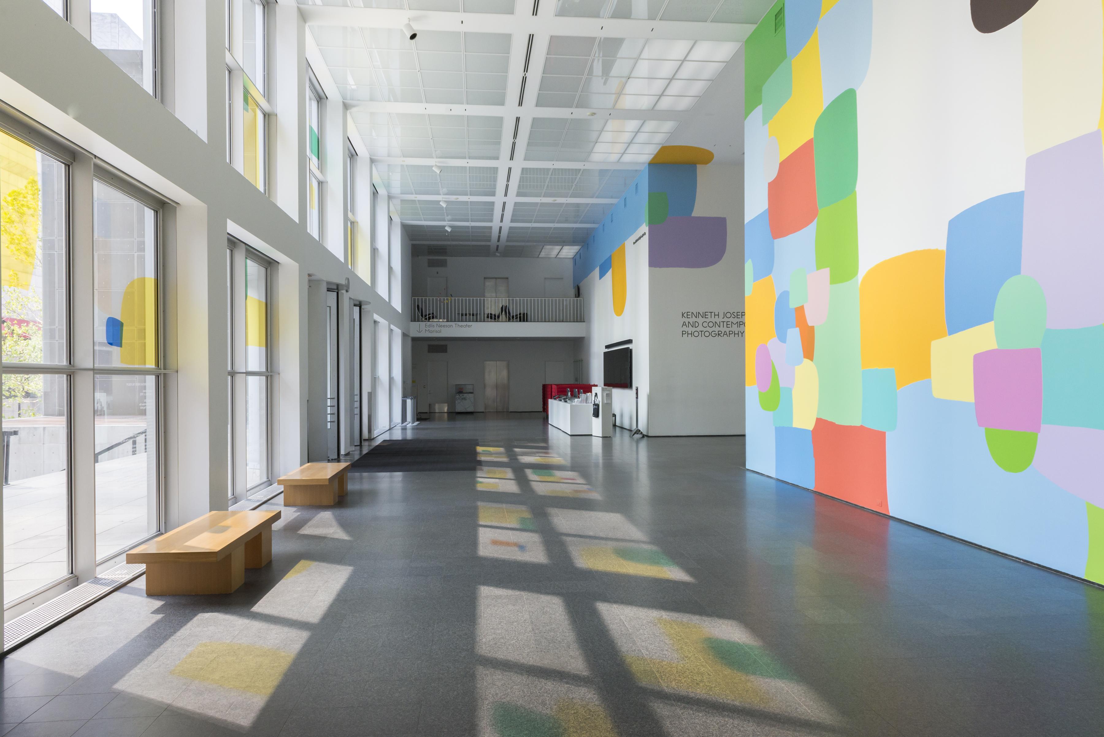 The MCA Atrium features a prominent, colorful mural on multiple walls. Colored panels on the windows create colorful shadows on the floor.