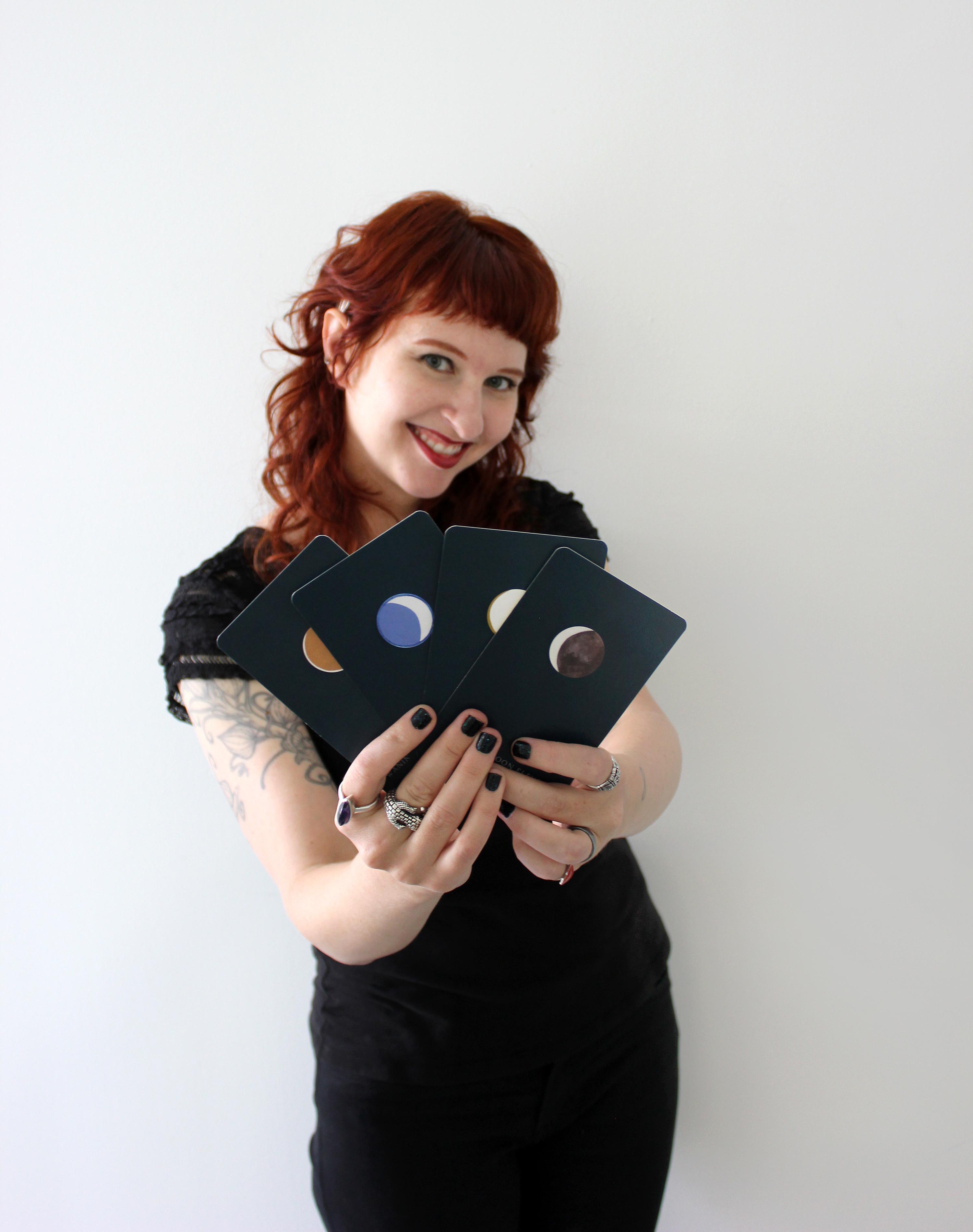 A person holds four large cards with moons on them, displaying them to you in a fan.