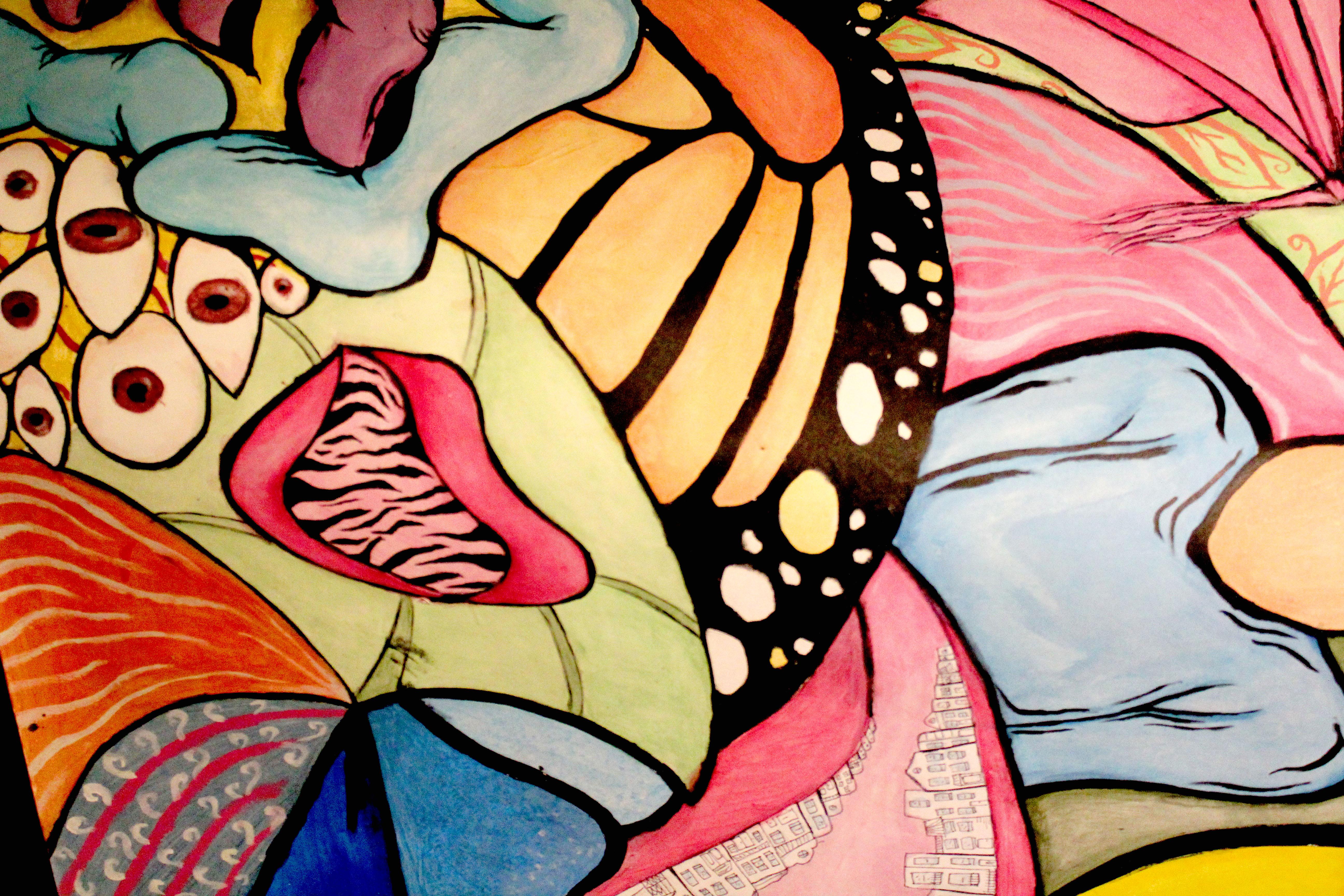 A brightly colored mural with overlapping abstract and partially figurative images, such as eyeballs and a butterfly wing.