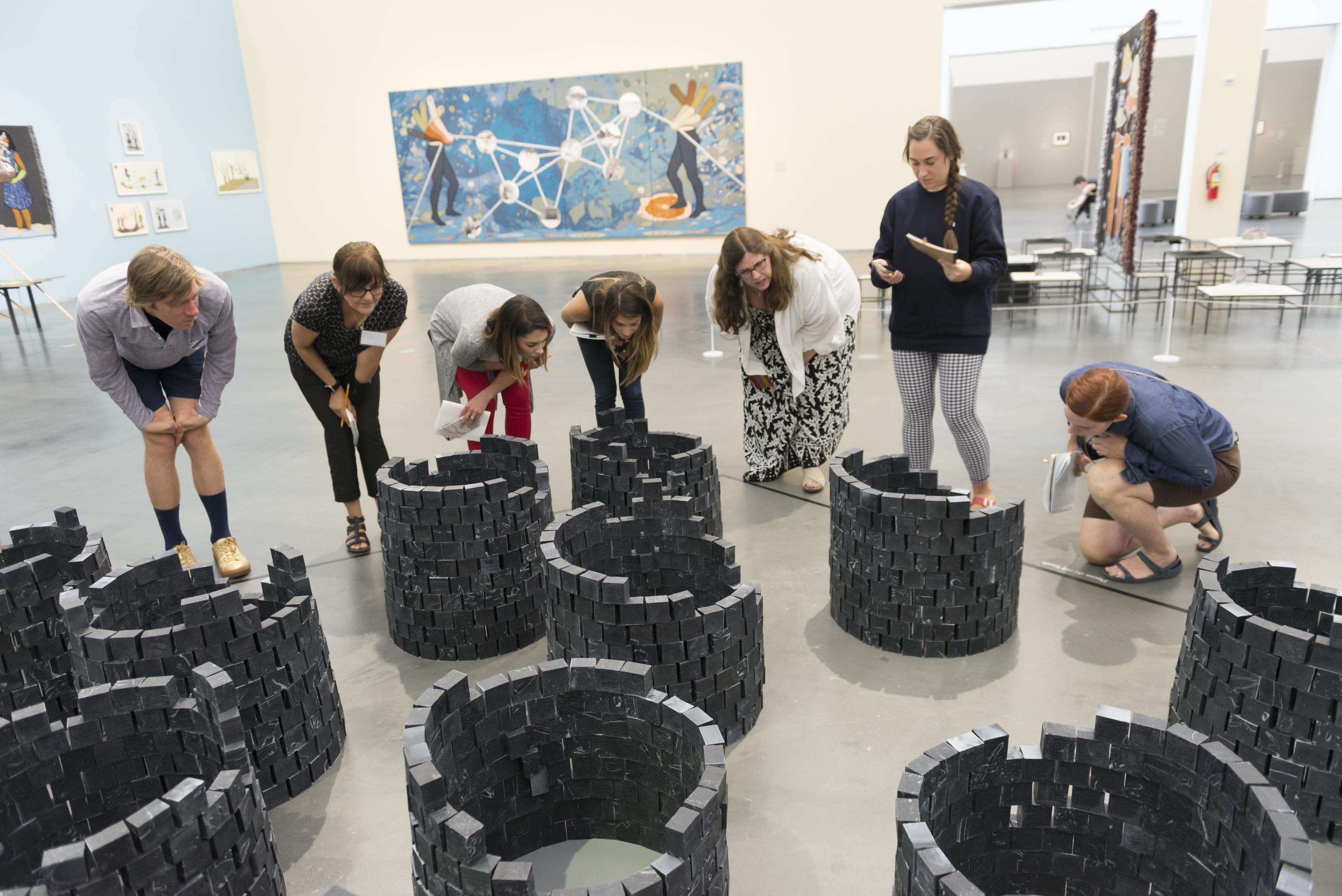 A group hunching down to get a closer work at art installation