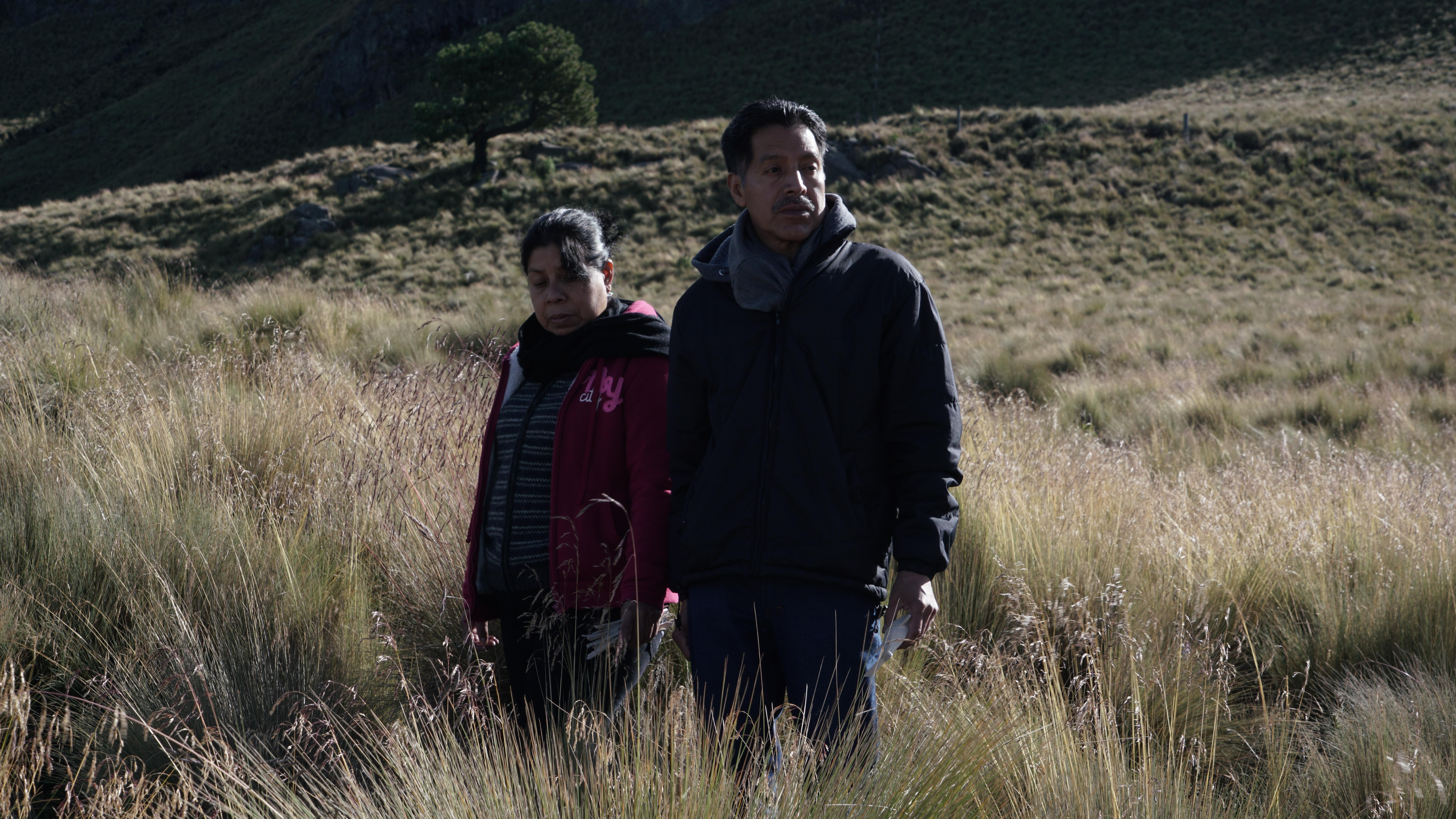 Two adults stand in an open field.