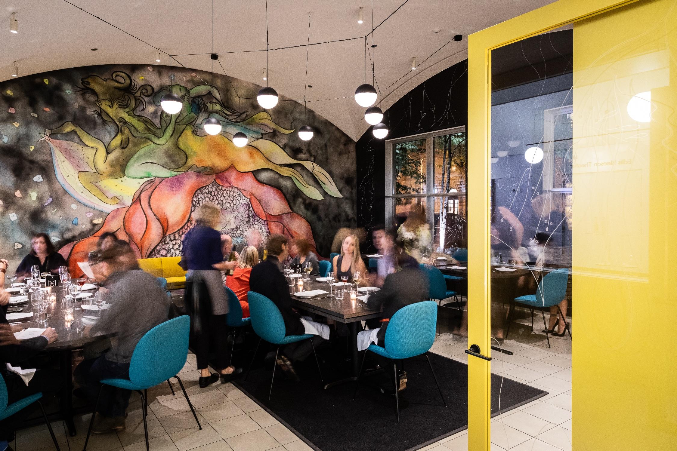 Small dining room with three different tables captured over time so the diners are slightly blurry.