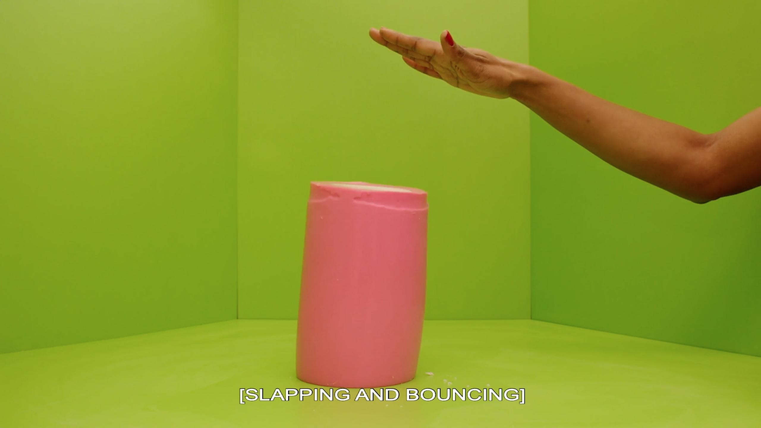 An arm extends into a lime-green room. A pink, gelatinous cylinder appears to have been slapped by the hand. Text on the image says [SLAPPING AND BOUNCING].