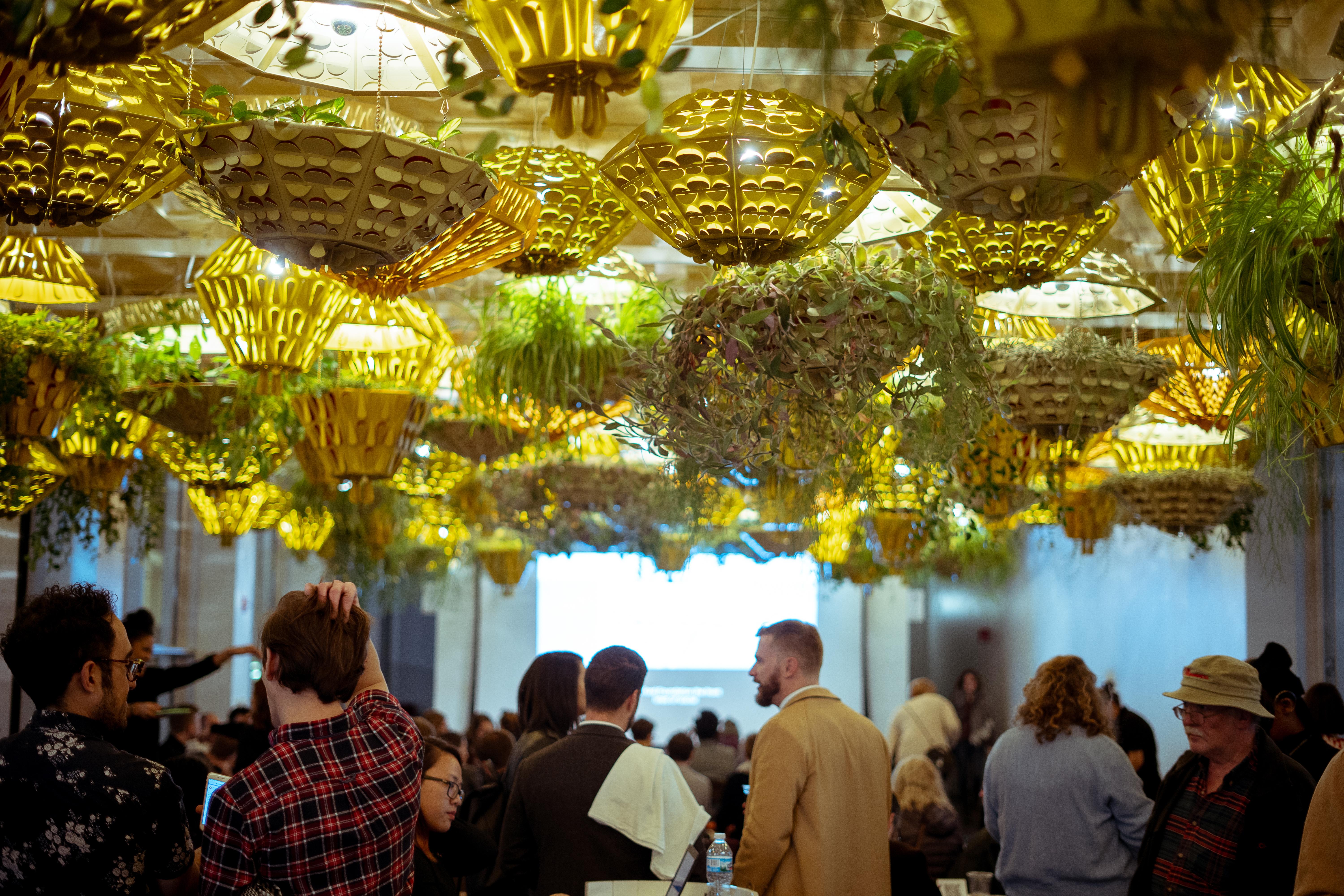 People gather under the ceiling light planters in the MCA Commons.