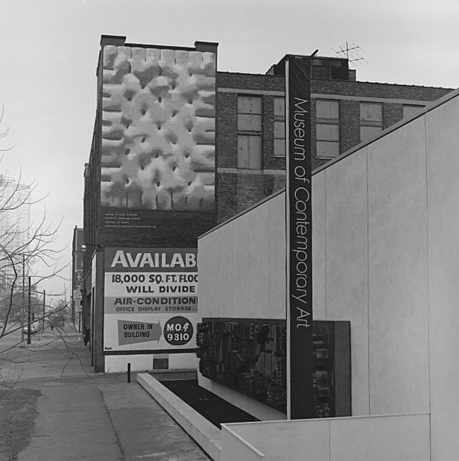 The exterior of a brick building beside a museum features a billboard depicting a gigantic soda cracker.