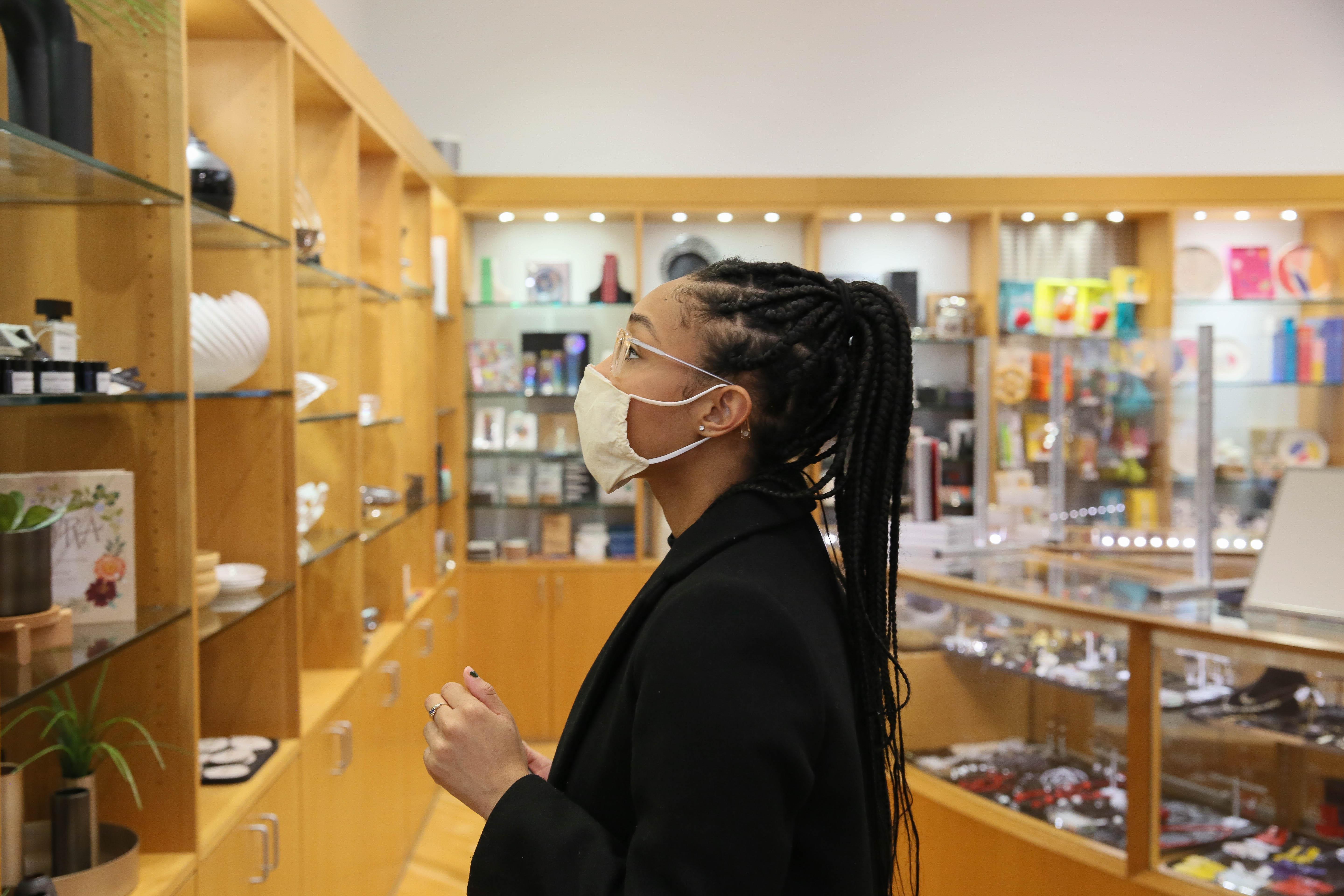 A woman in a mask browsing items at the MCA store