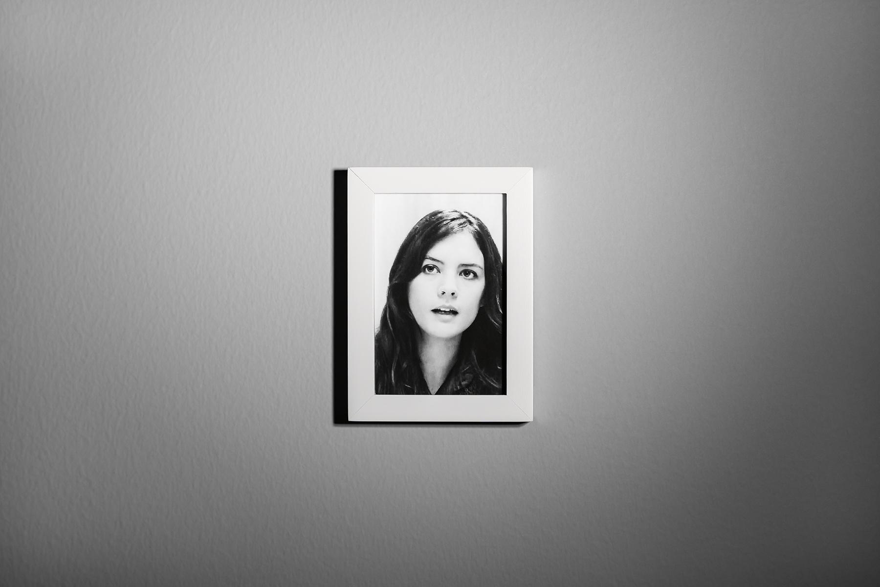 A framed portrait of a woman hangs on a wall