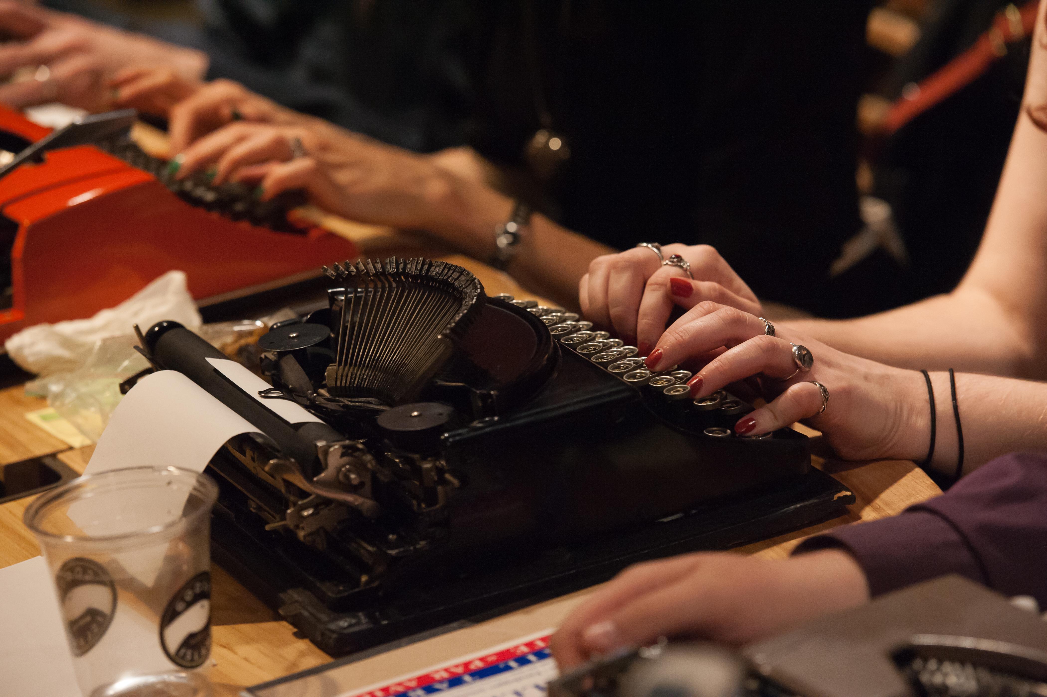 closeup on several hands at several typewriters