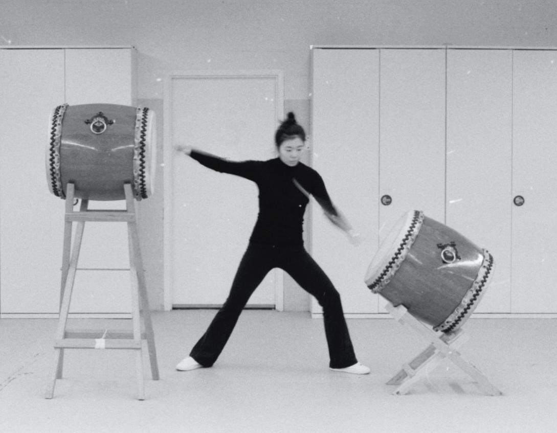 Kioto Aoki striking two large upright drums