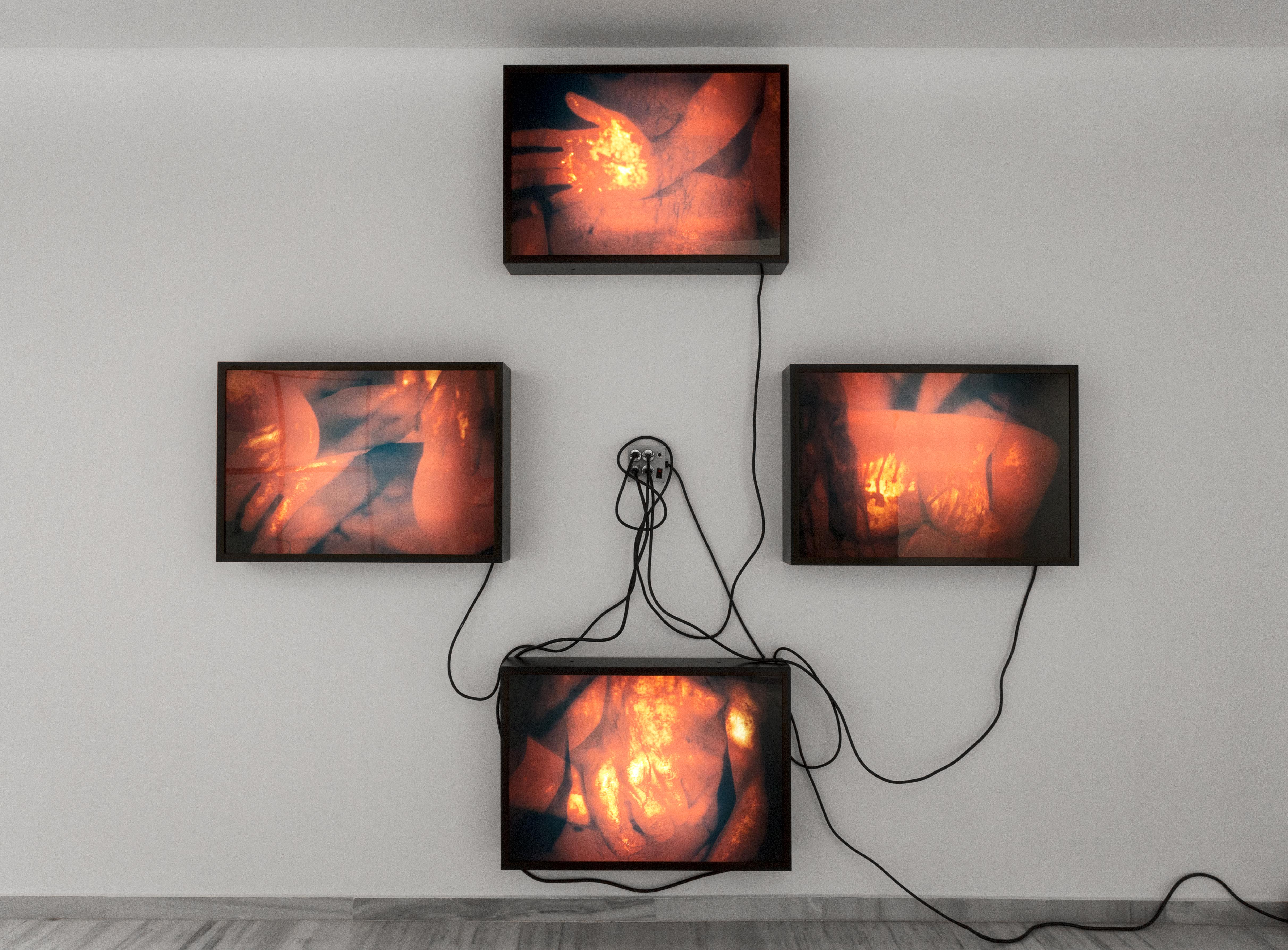 four lightboxes displaying abstract warm-toned images, arranged in a cross with cords dangling